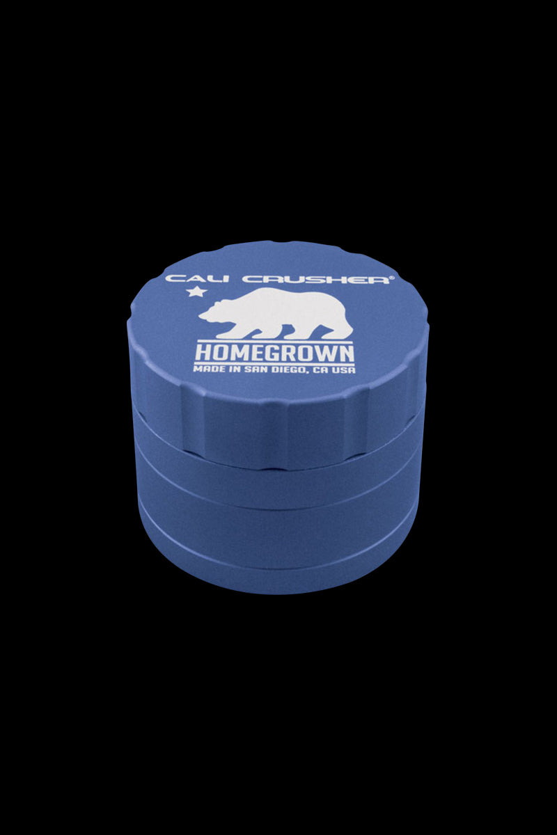 Top-down view of a blue Cali Crusher Homegrown 4 Piece Grinder with white bear logo and stacked ridged chambers against a black background