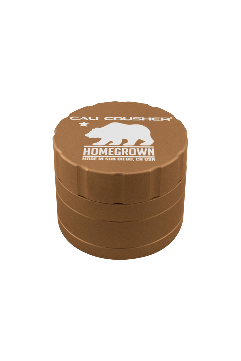 Top-down view of a bronze Cali Crusher Homegrown 4 Piece Grinder with white bear logo and ridged sides against a white background