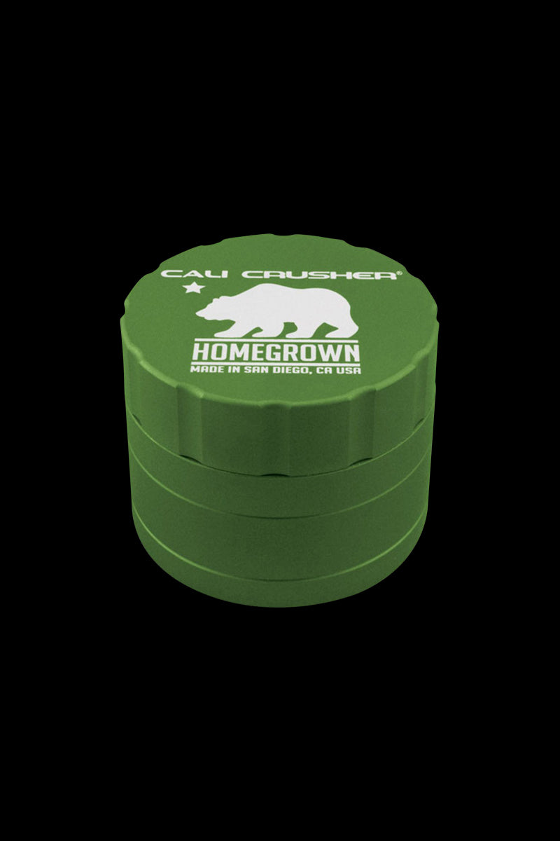 Angled front view of a green Cali Crusher Homegrown 4 Piece Grinder with white bear logo and text on the lid against a black background
