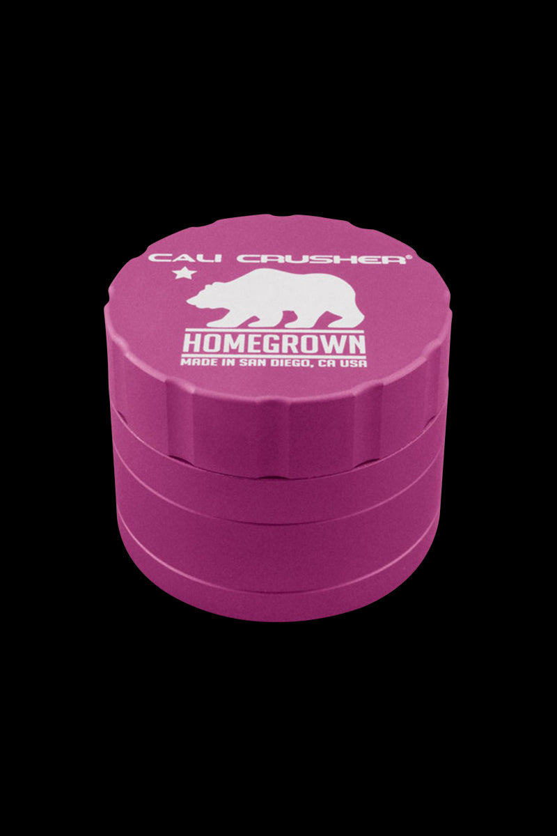 Angled top-down view of a red Cali Crusher Homegrown 4 Piece Grinder with white bear logo against a black background