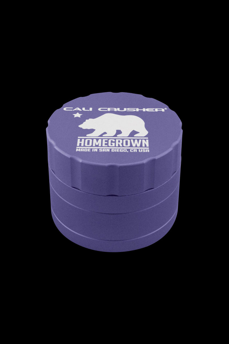 Angled front view of a green Cali Crusher Homegrown 4 Piece Grinder with its white bear logo and "HOMEGROWN" text visible on the top against a black background