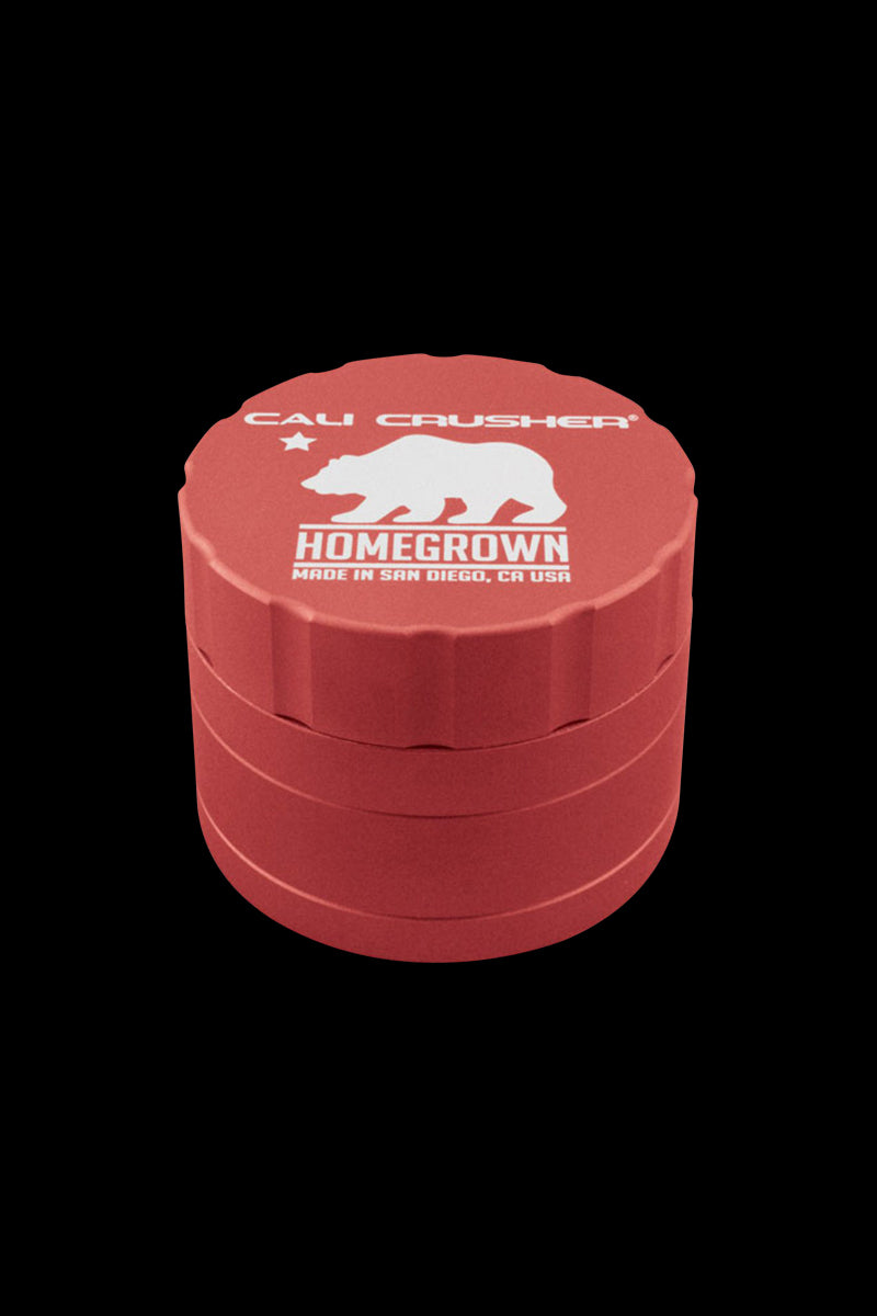 Close-up front view of a purple Cali Crusher Homegrown 4 Piece Grinder with its white bear logo and ridged stacked sections against a black background.