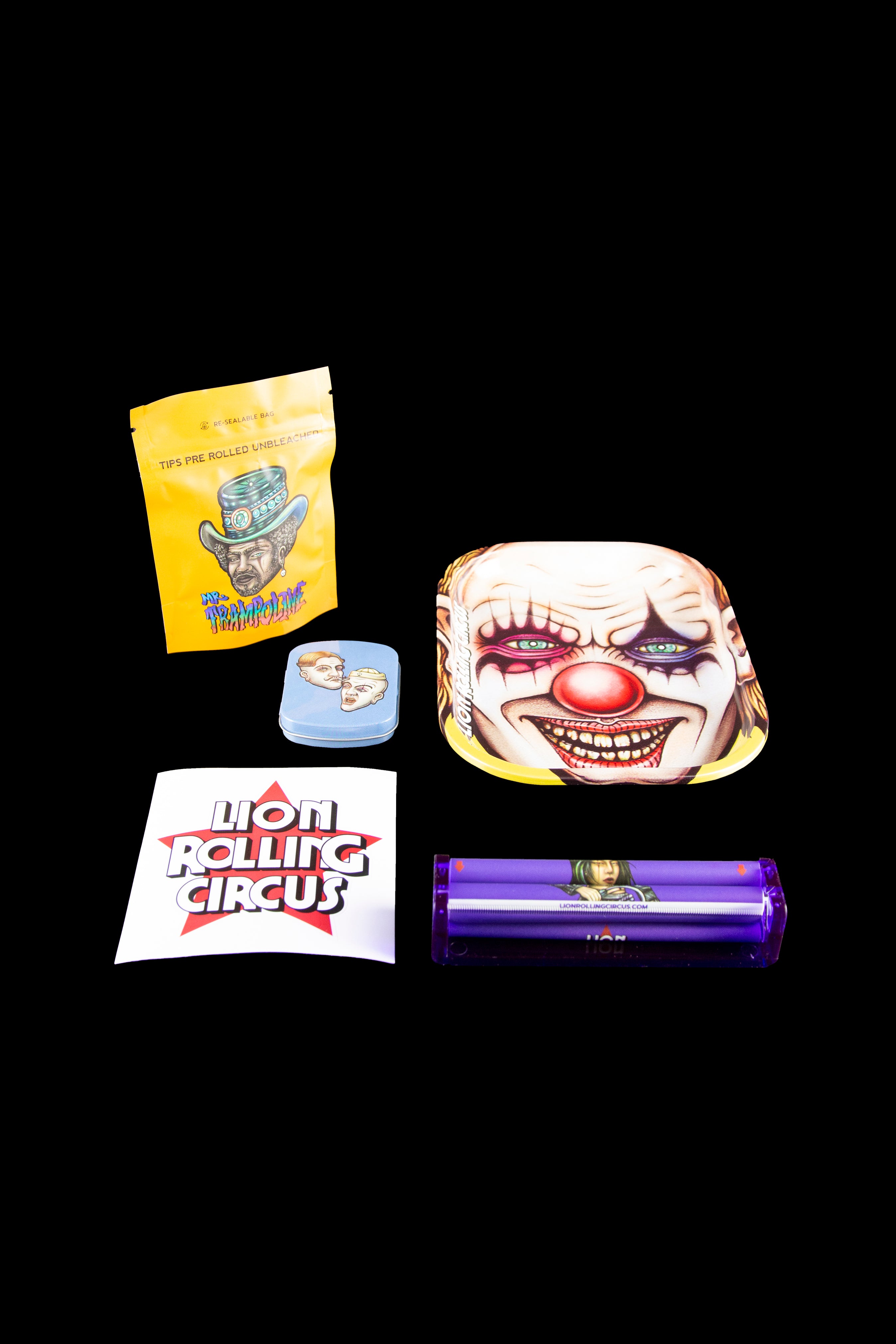 Cannabis accessories including pre-rolled tips, a metal tin with a clown design, a lighter, and packaging for “Lion Rolling Circus” displayed on a black surface.