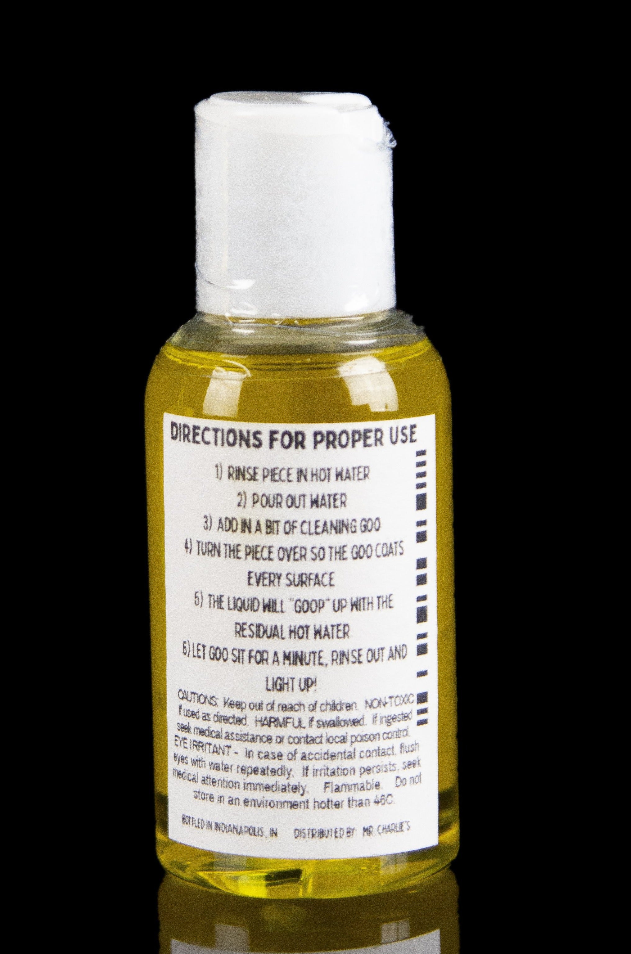 Close-up of a yellow cleaning solution bottle with instructions for cleaning cannabis pipes, labeled “Directions for Proper Use.”