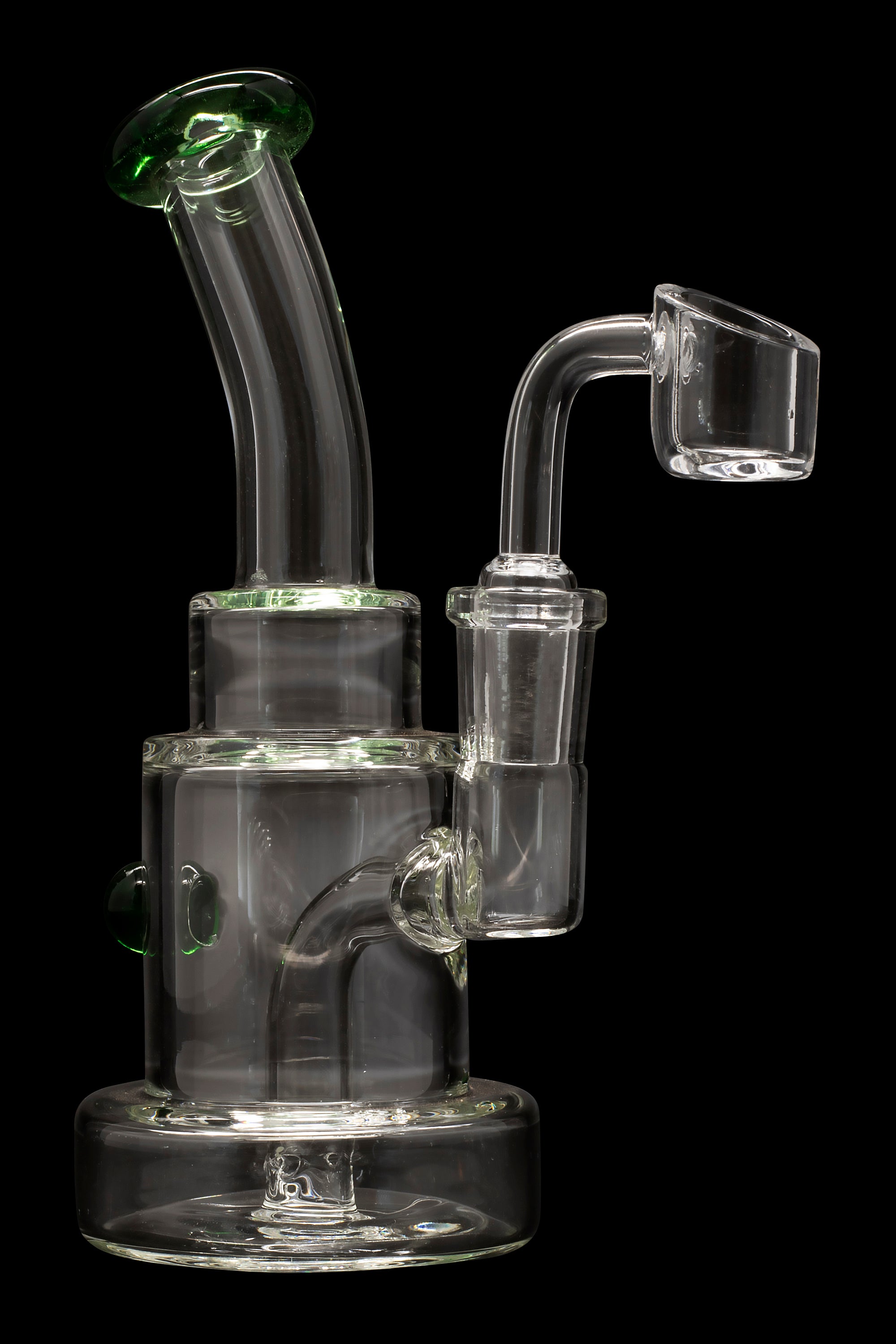 Clear glass dab rig with green accents and a quartz banger.