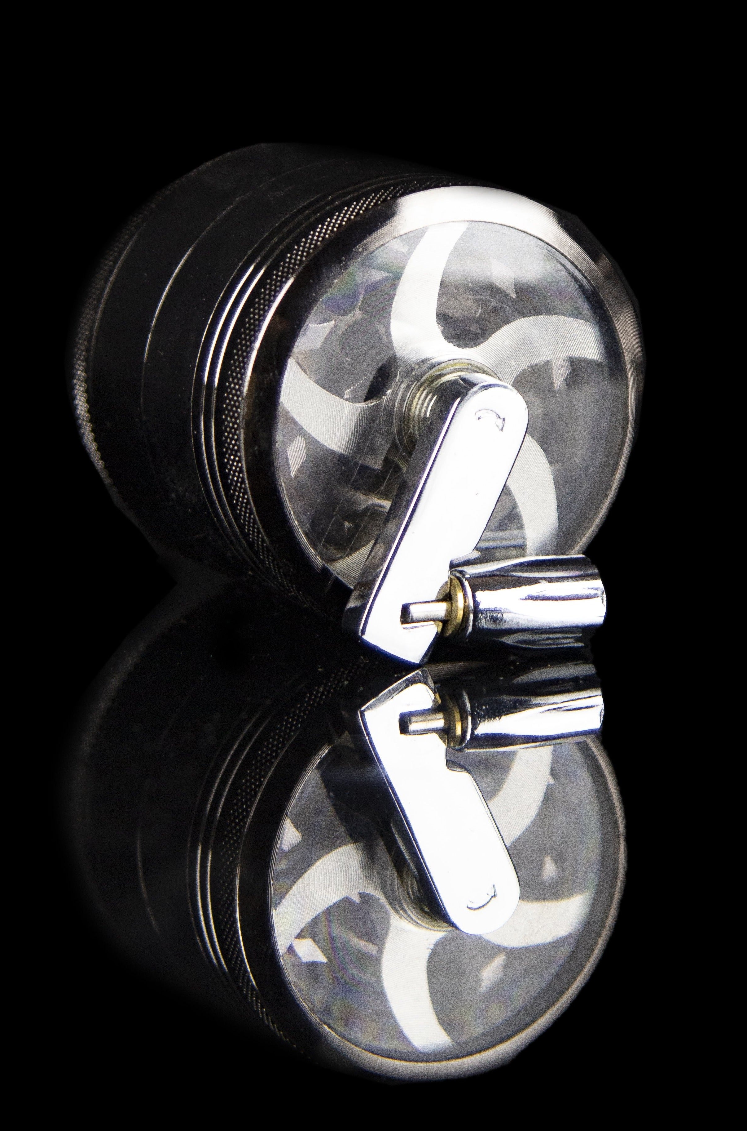 Clear glass grinder with black metal base and reflective surface.