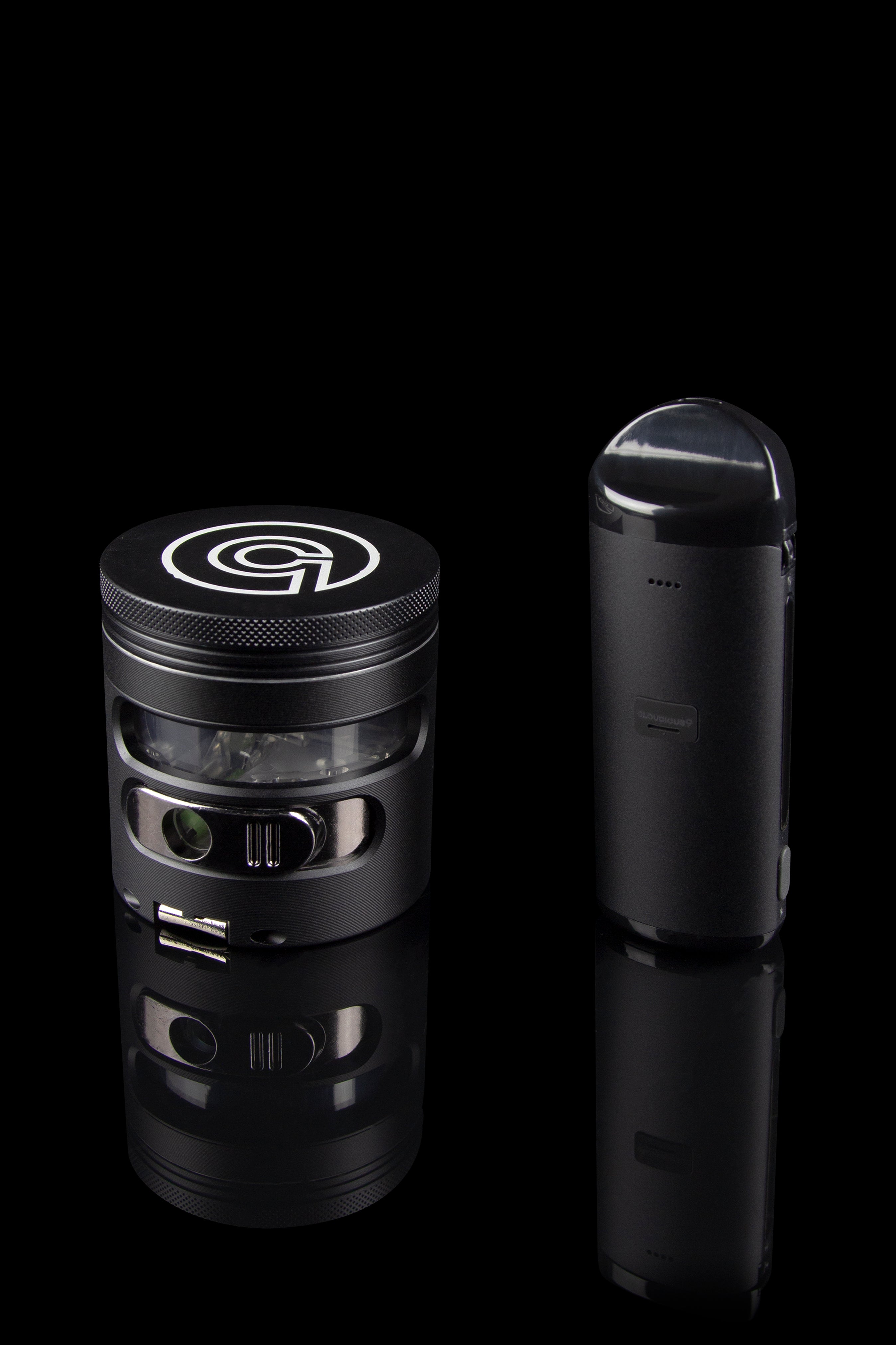 Black cannabis grinder and vaporizer pen displayed on a reflective surface.