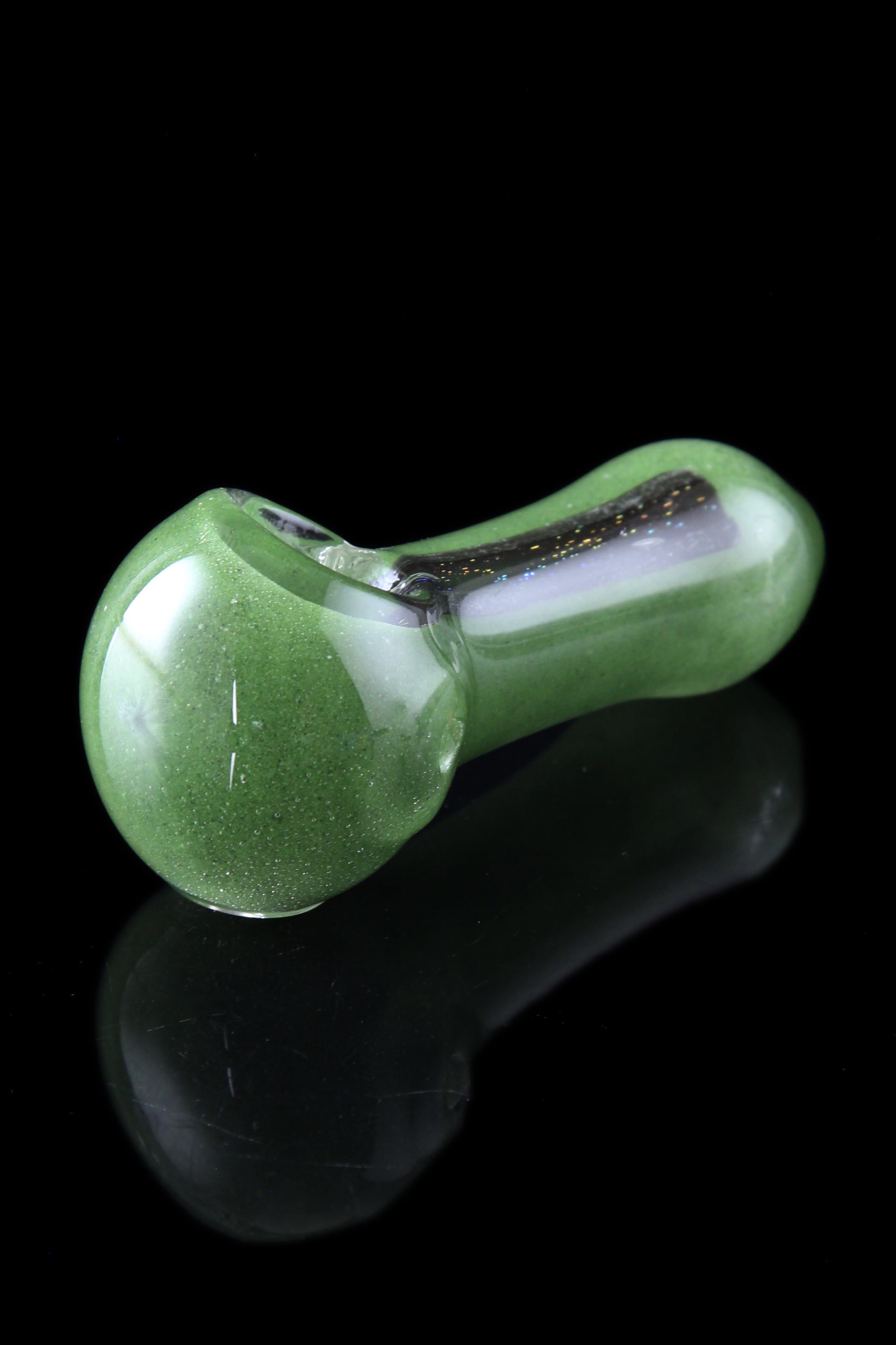 Green glass pipe with a speckled finish, displayed on a reflective black surface.