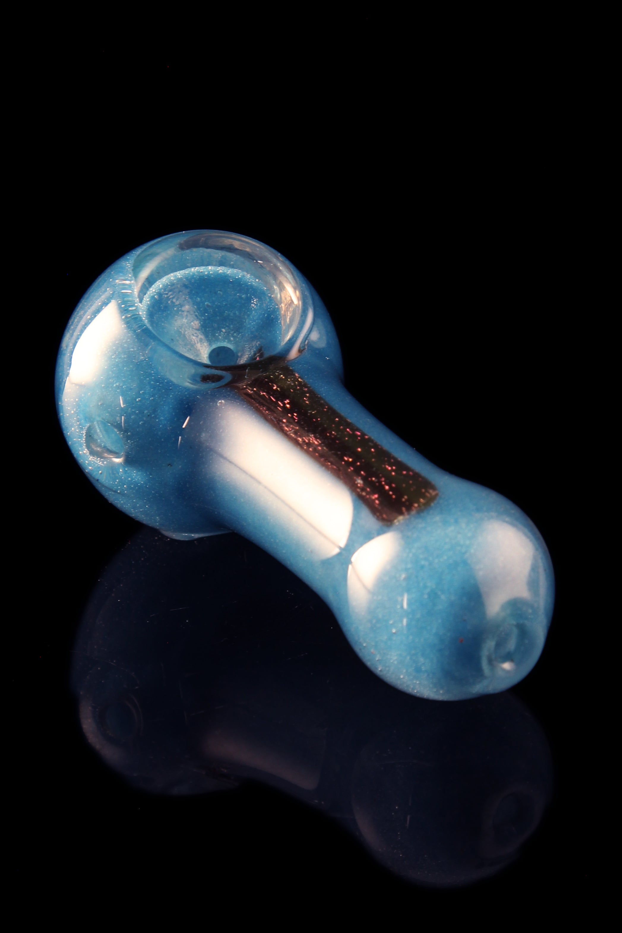 A close-up, angled view of the Glassheads "Dichro Strip" Spoon, showcasing its colorful, striped glass design and curved shape.