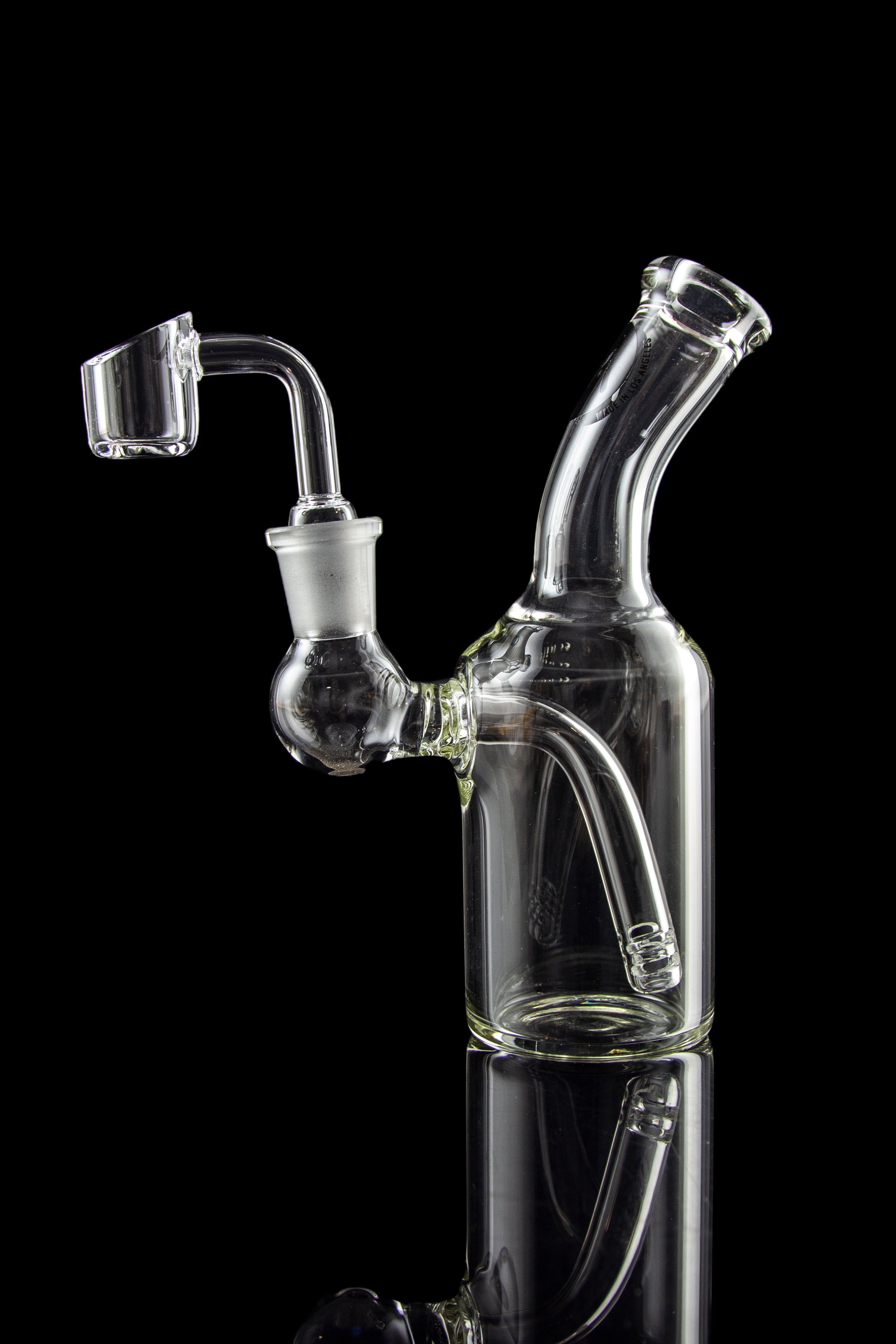 Clear glass dab rig with quartz banger, isolated on black.
