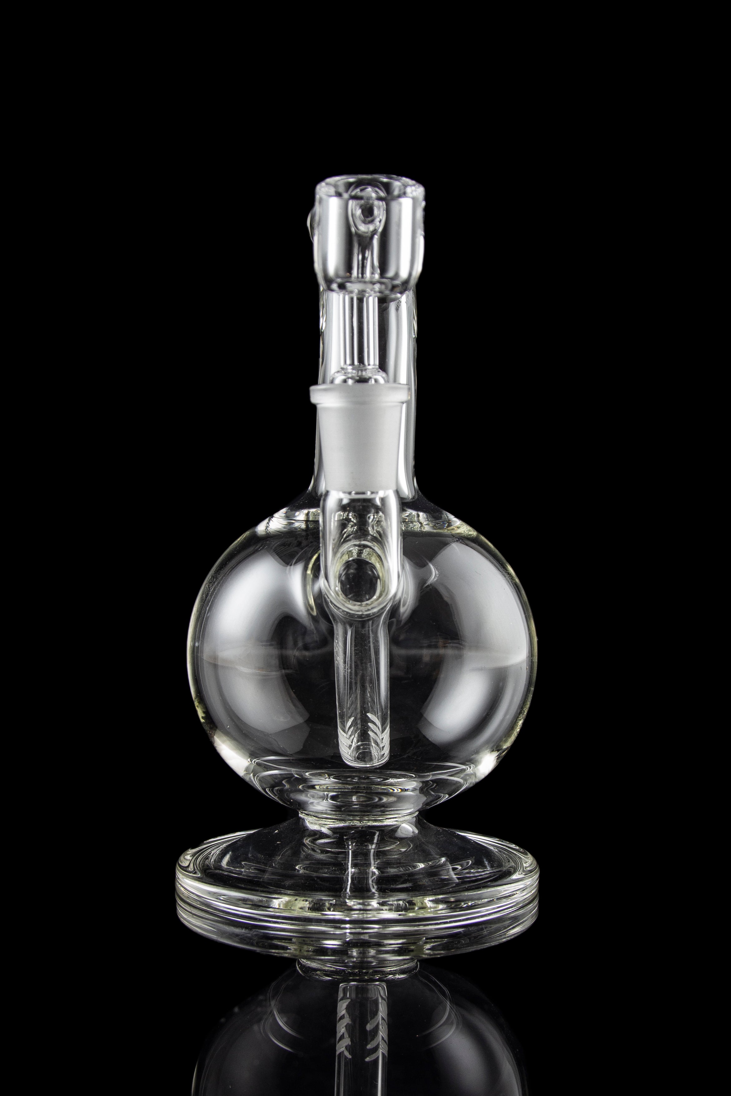 Clear glass water pipe (rig) with spherical body and intricate internal pathways, reflecting on a dark surface.