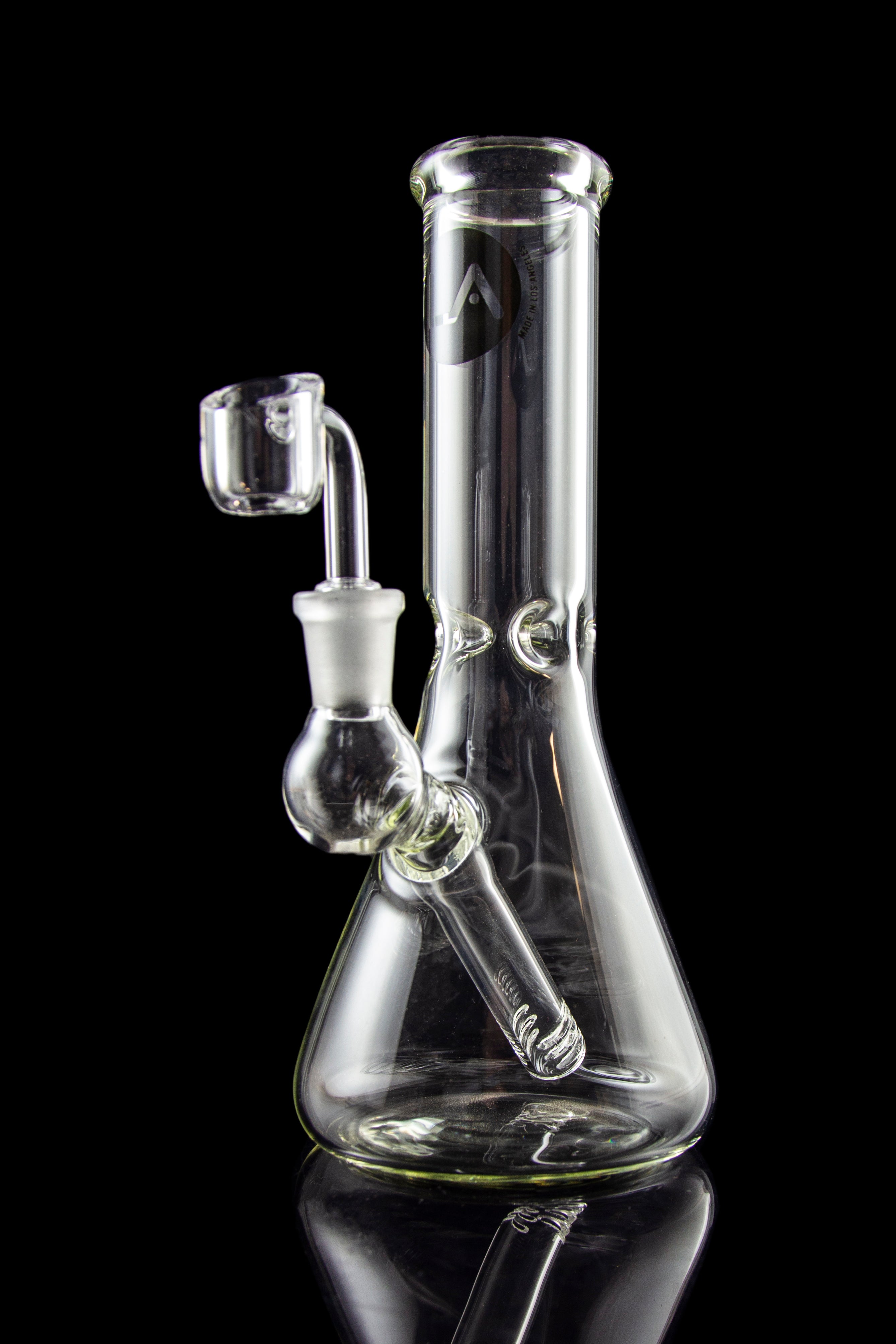 Clear glass water pipe (bong) with a quartz banger, studio shot on a black reflective surface.