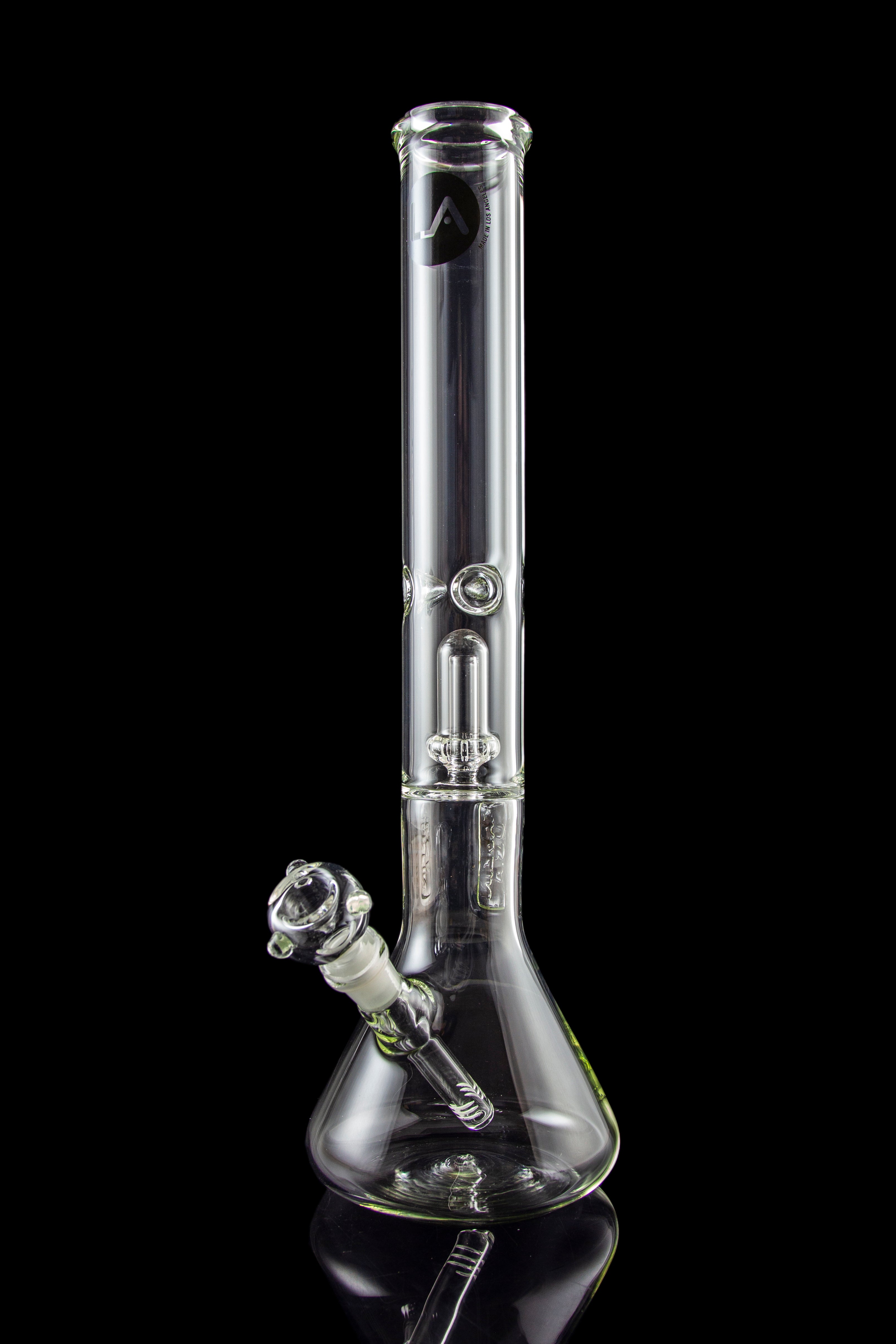 Clear glass bong with intricate percolators, reflecting on a black surface.