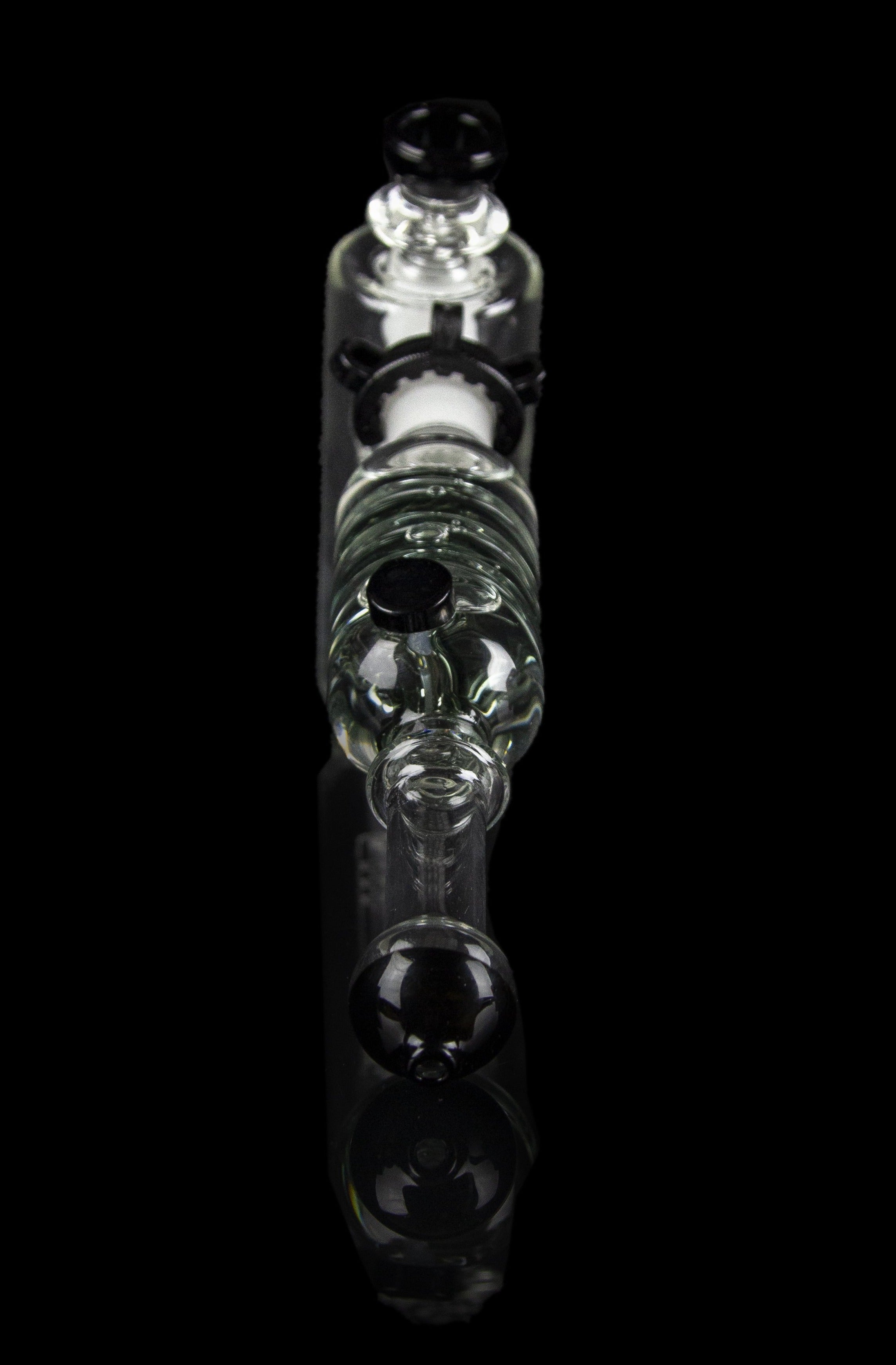 Clear glass bubbler water pipe with skull-shaped chambers, isolated on black.
