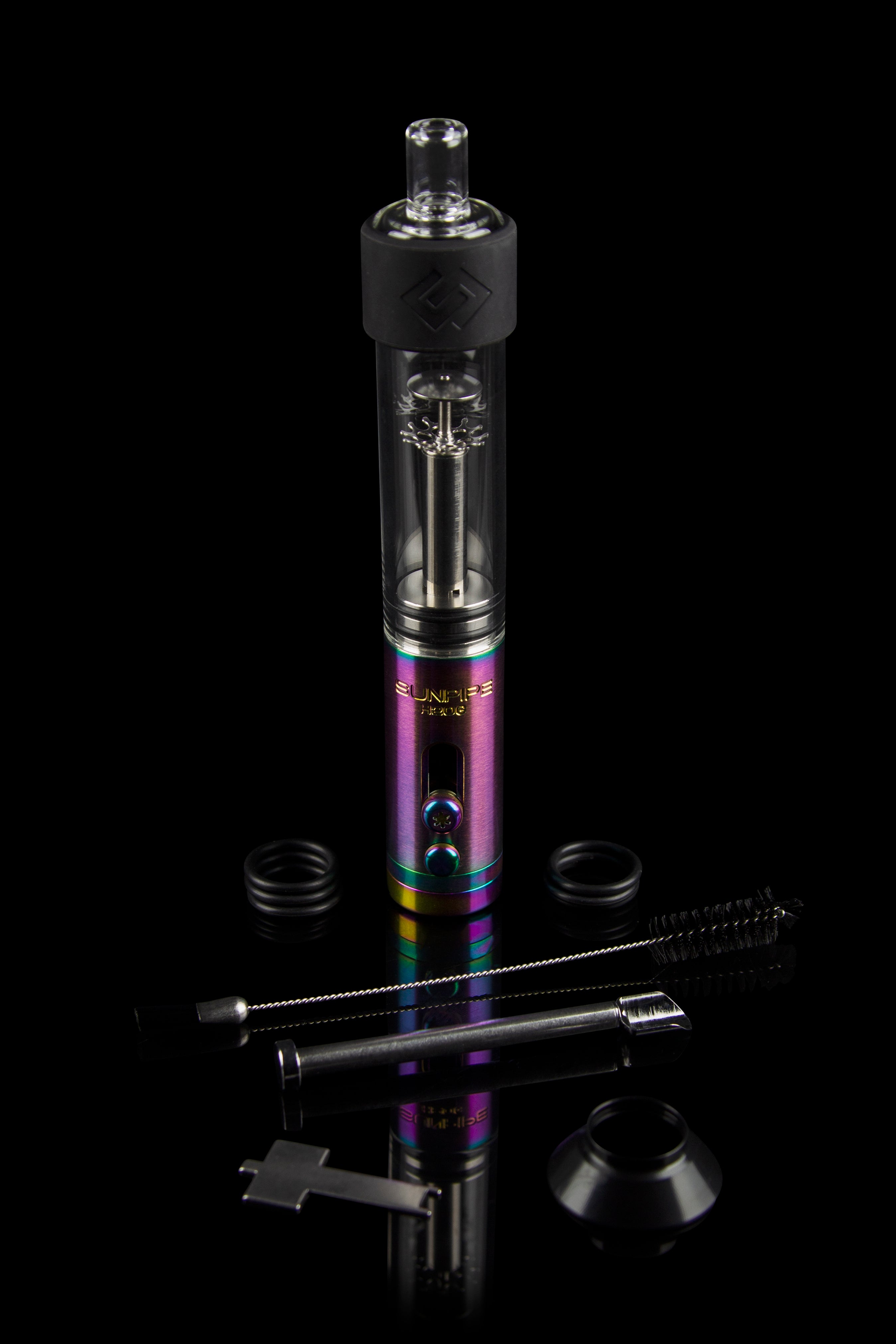 A sleek, colorful cannabis oil rig (dab rig) with glass and metal components, alongside cleaning tools, presented on a black reflective surface.