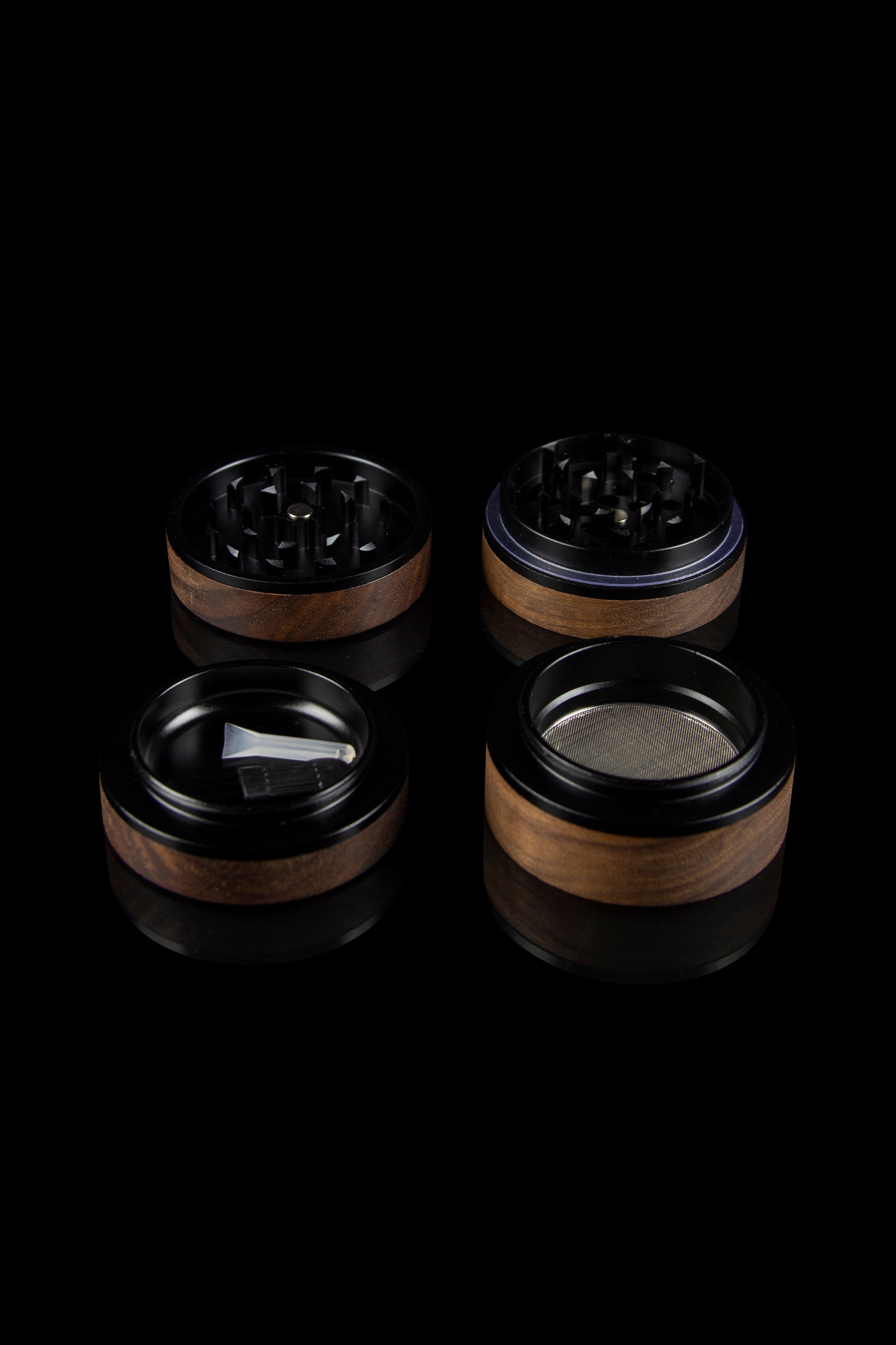 Four-piece wooden and metal cannabis grinder set on a black background.