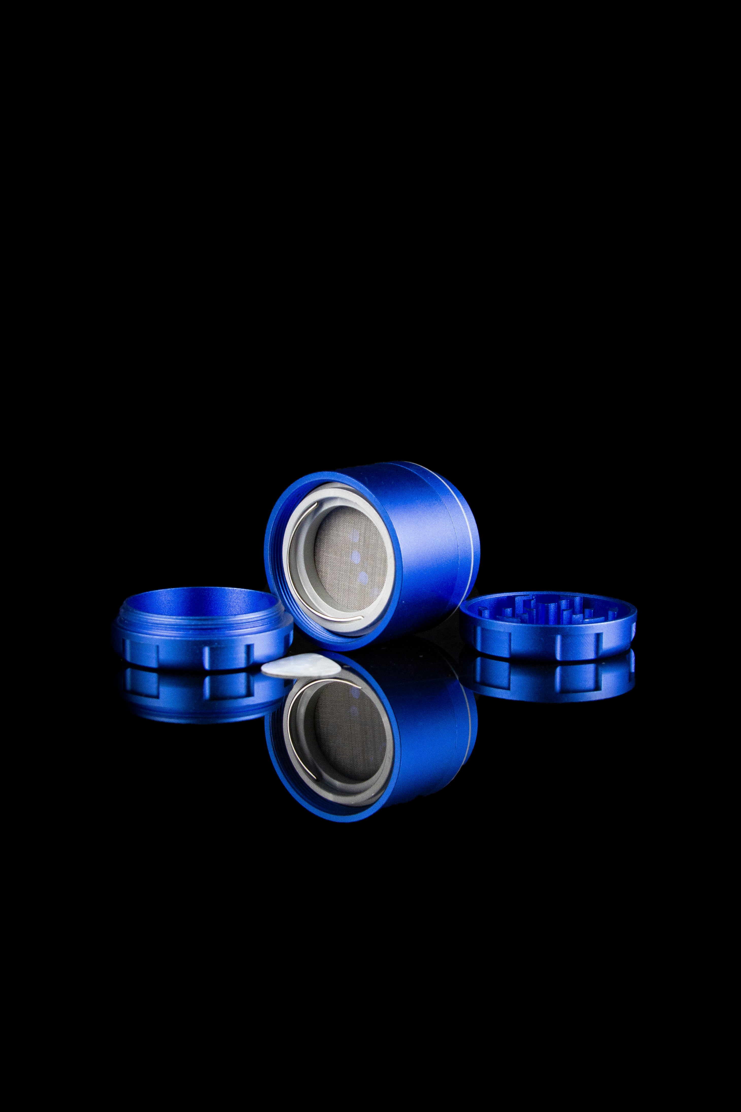 Blue cannabis grinder with metallic reflection on a black background.