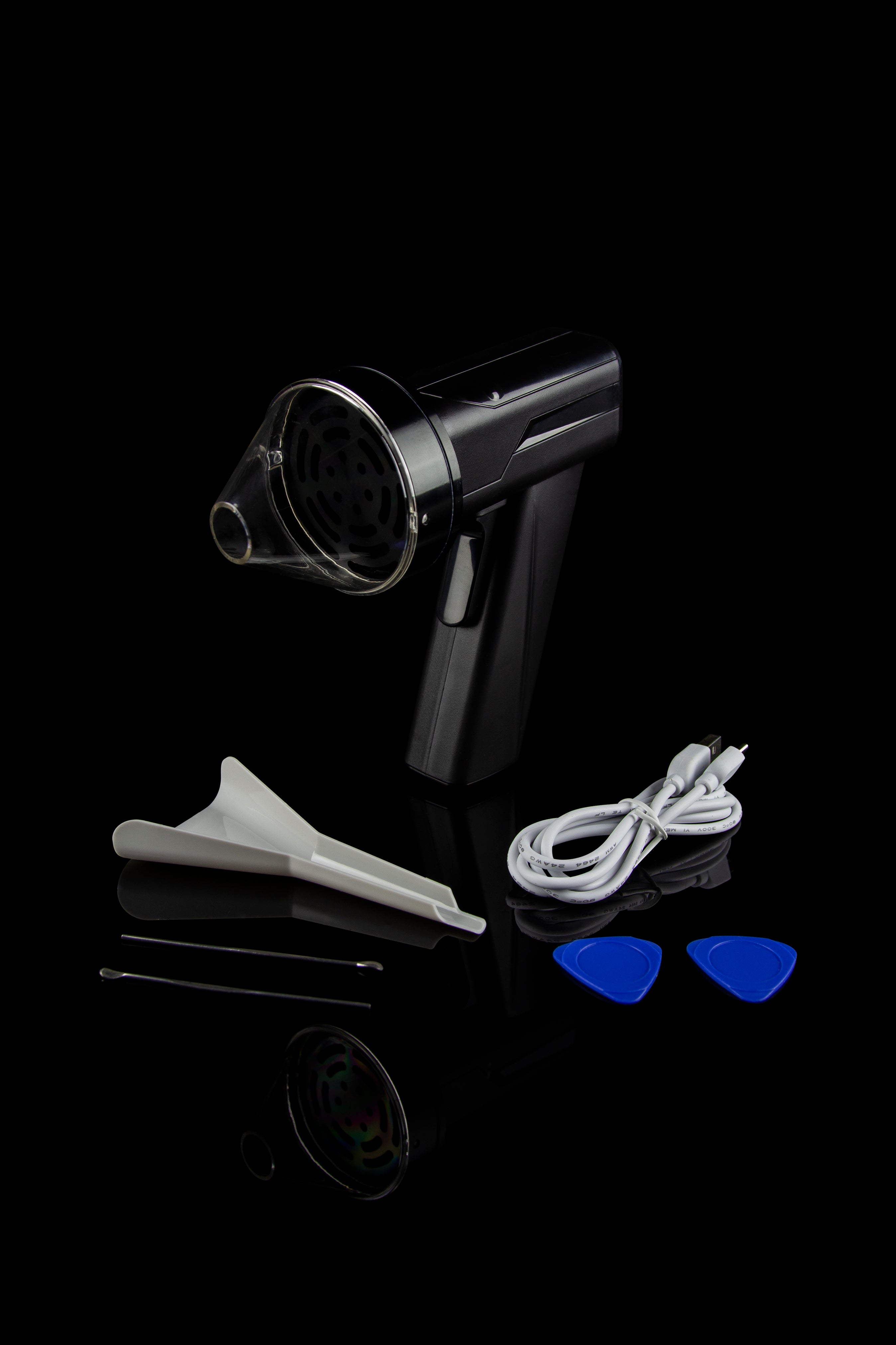 Cannabis vaporizer with included attachments and cleaning tools on a reflective black surface.