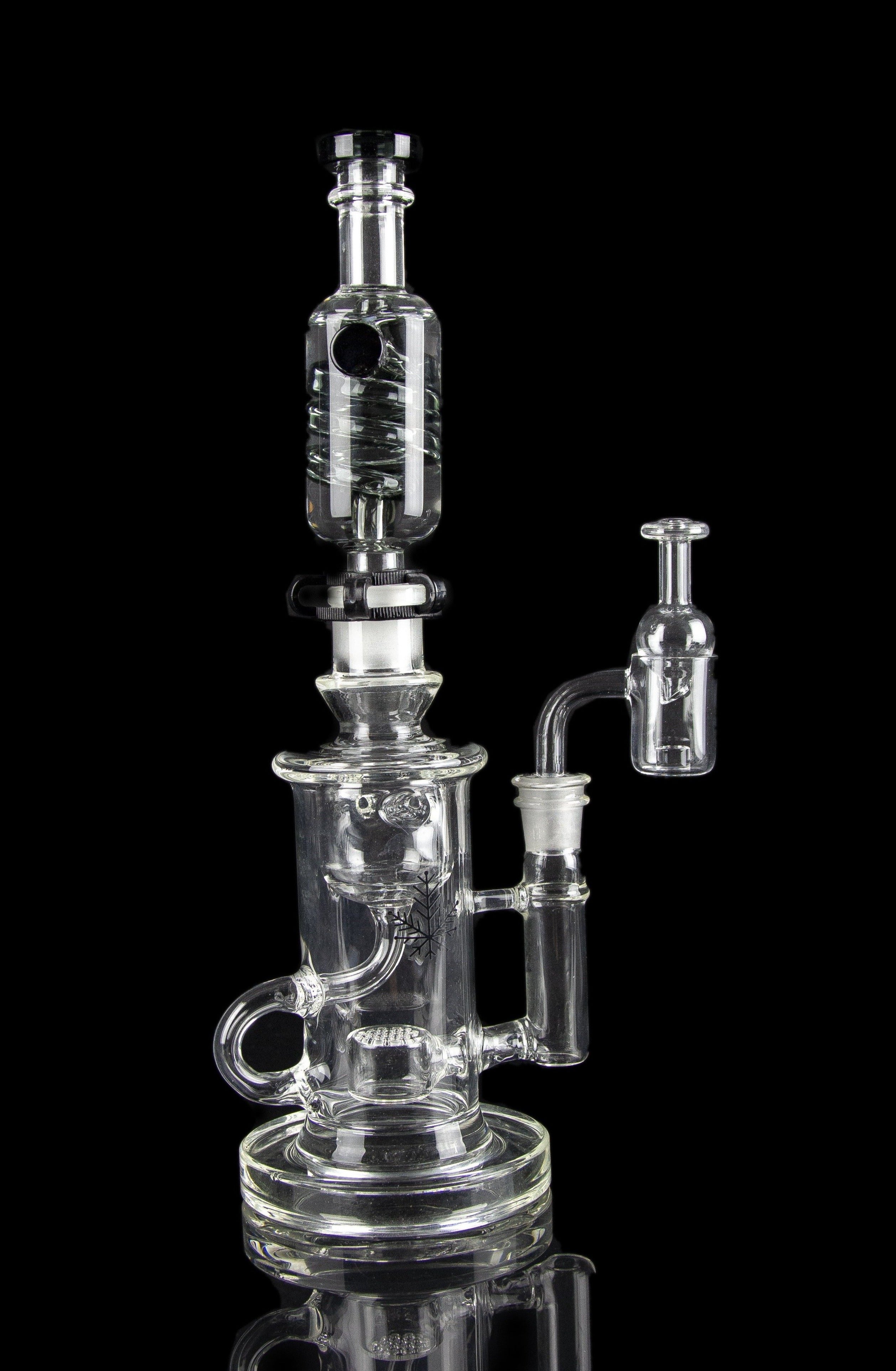 Clear glass water pipe (rig) with multiple chambers and a separate oil dome, isolated on a black background.