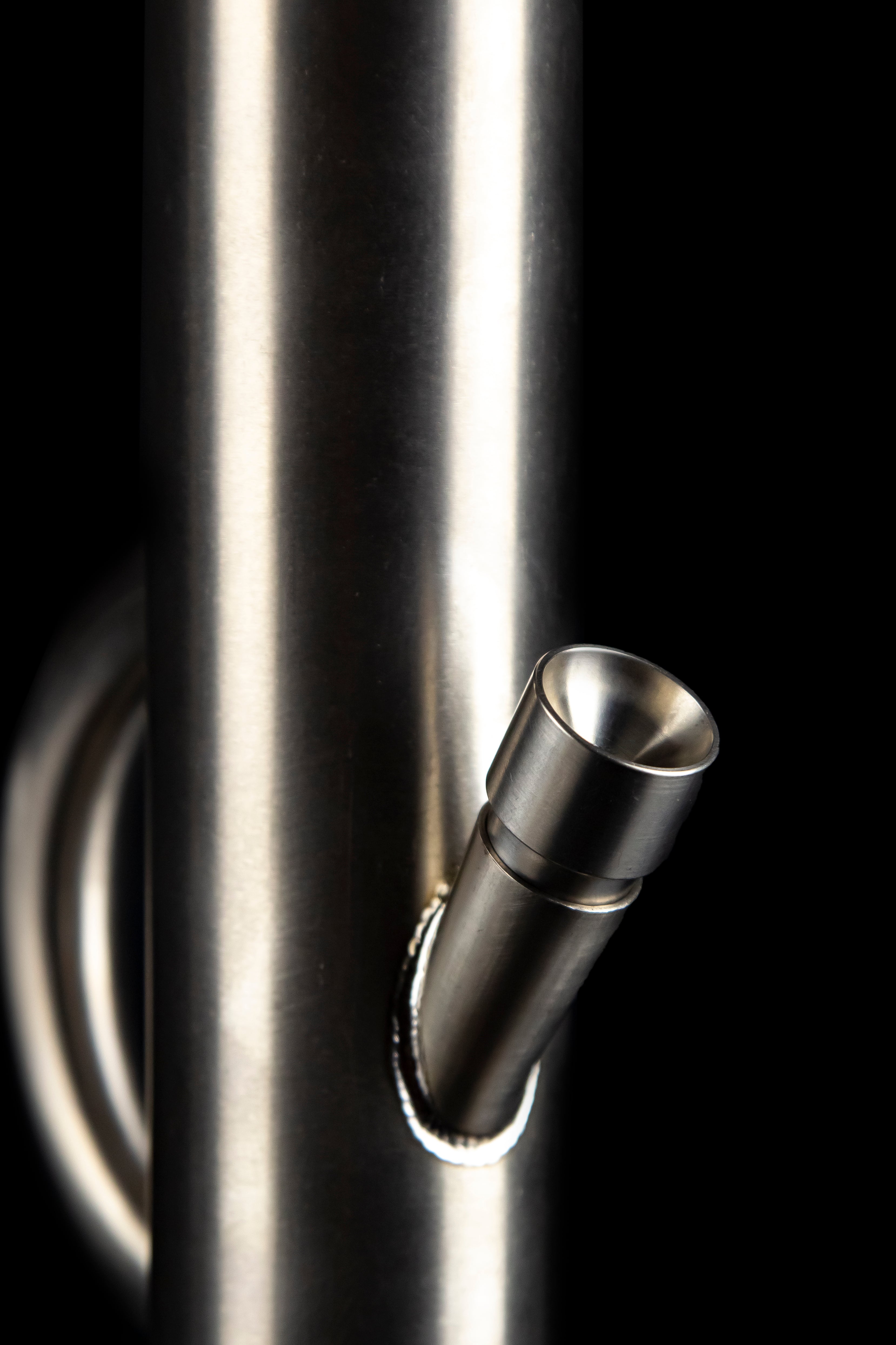 A close-up of a metallic cannabis pipe against a dark, illuminated background.