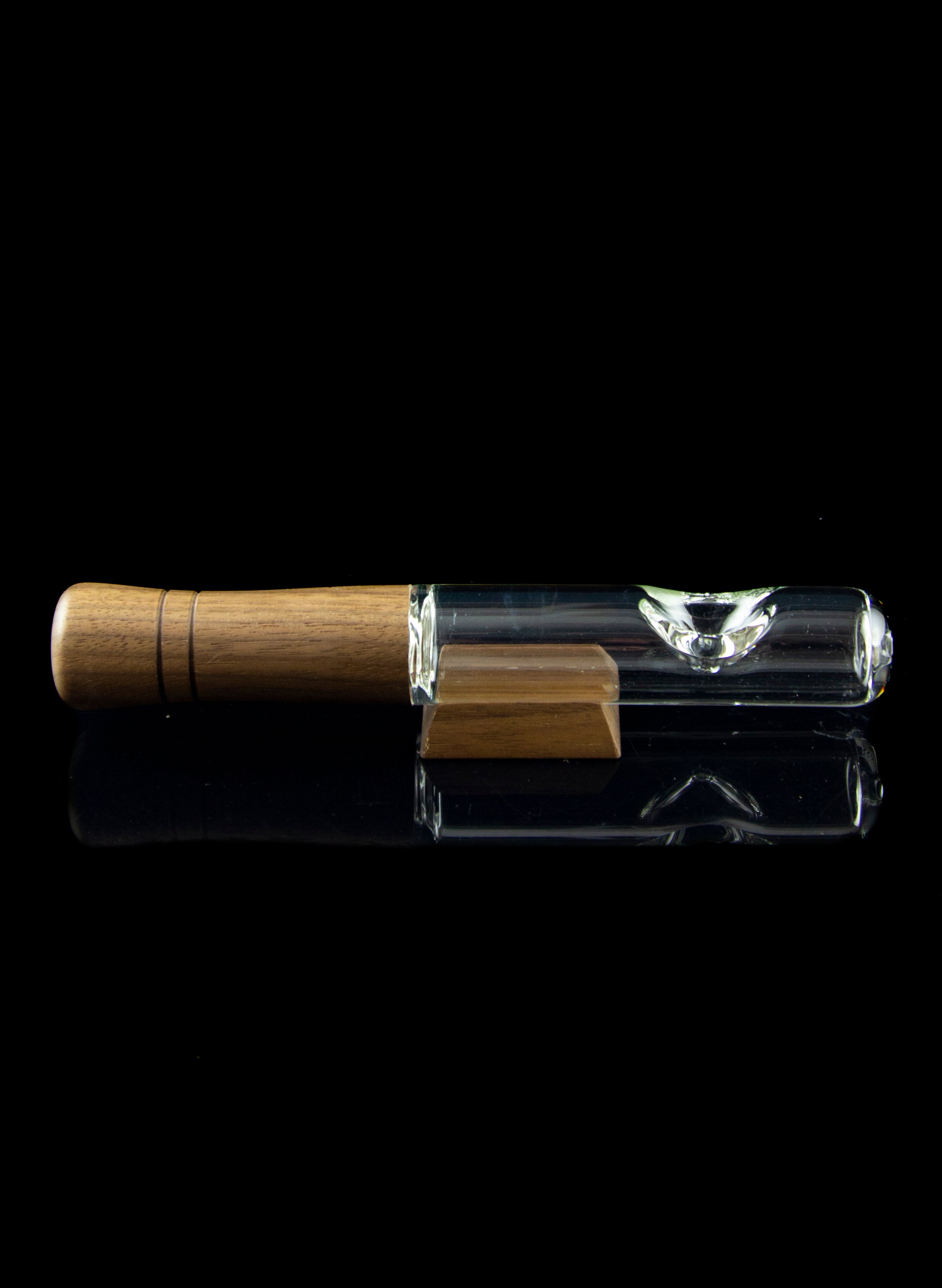 Wooden-tipped glass chillum with a second, empty chillum below, against a black background.