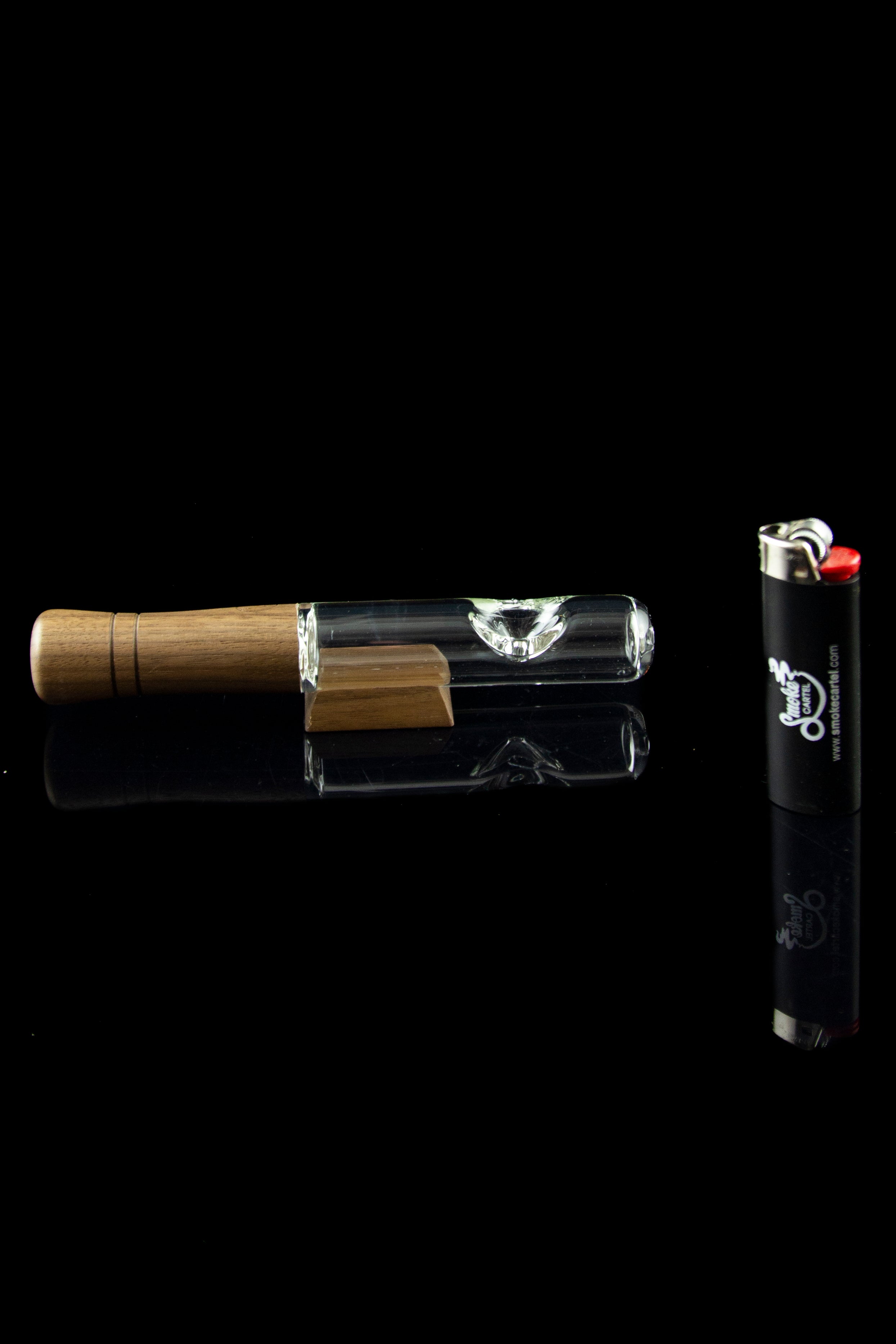 Glass cannabis pipe with wooden mouthpiece and lighter on black background.