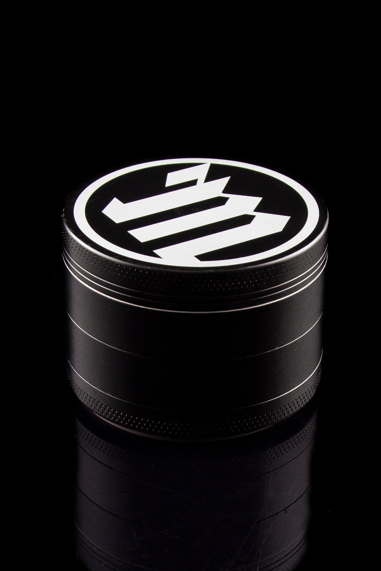 Black metal cannabis grinder with a white logo on top.