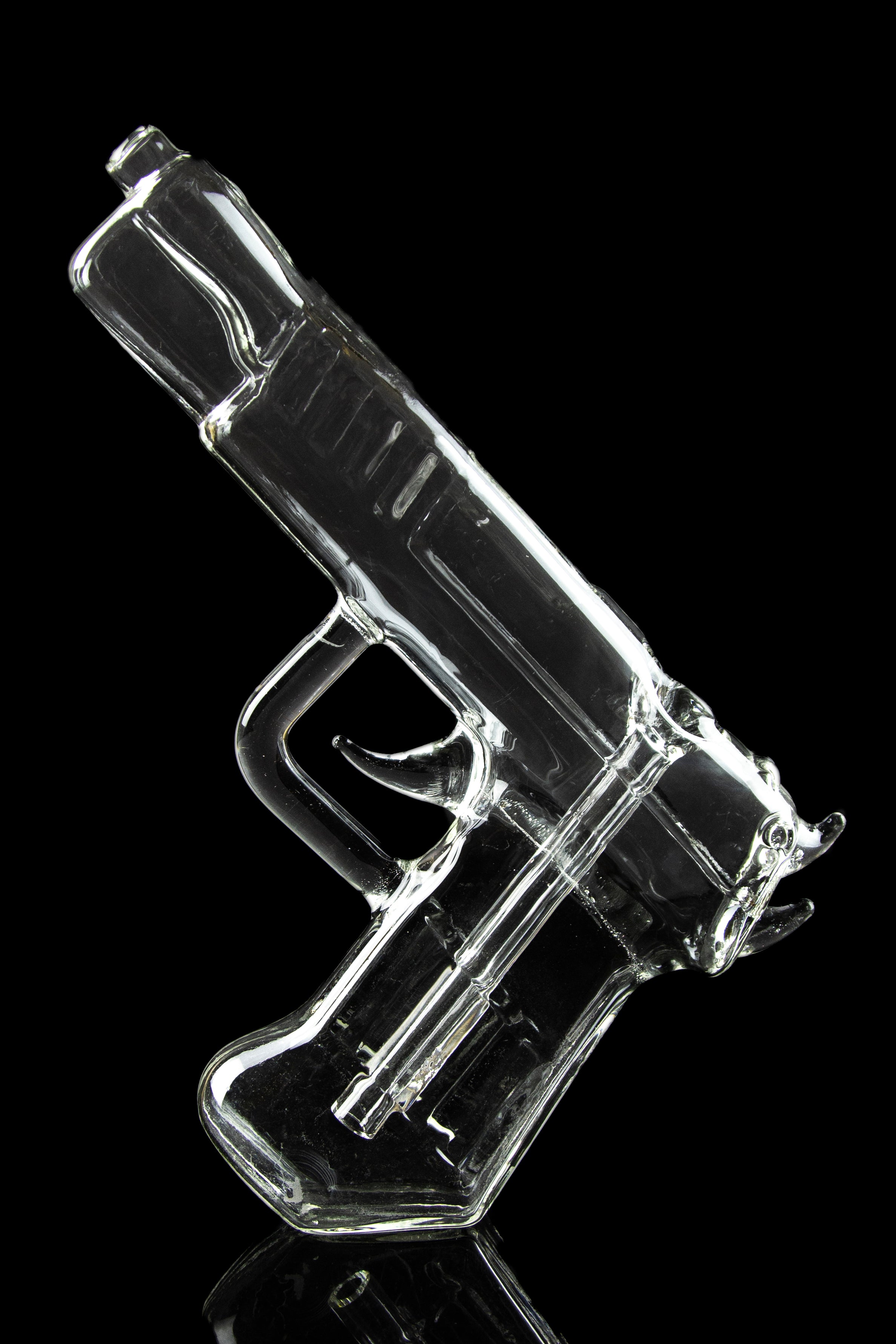 Clear glass pipe shaped like a handgun, reflecting on a dark surface.