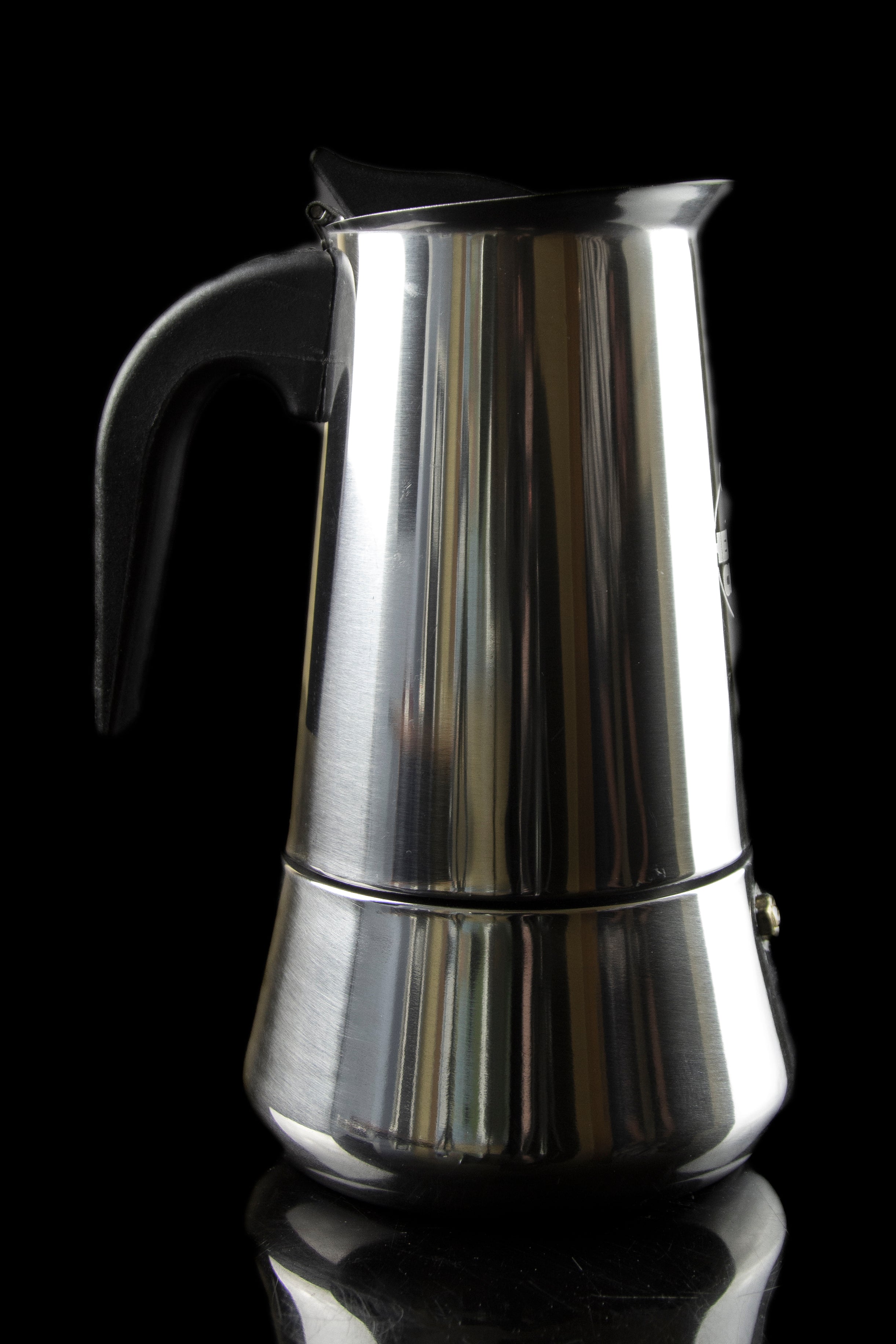 Silver stovetop espresso maker, reflecting light, against a black background.