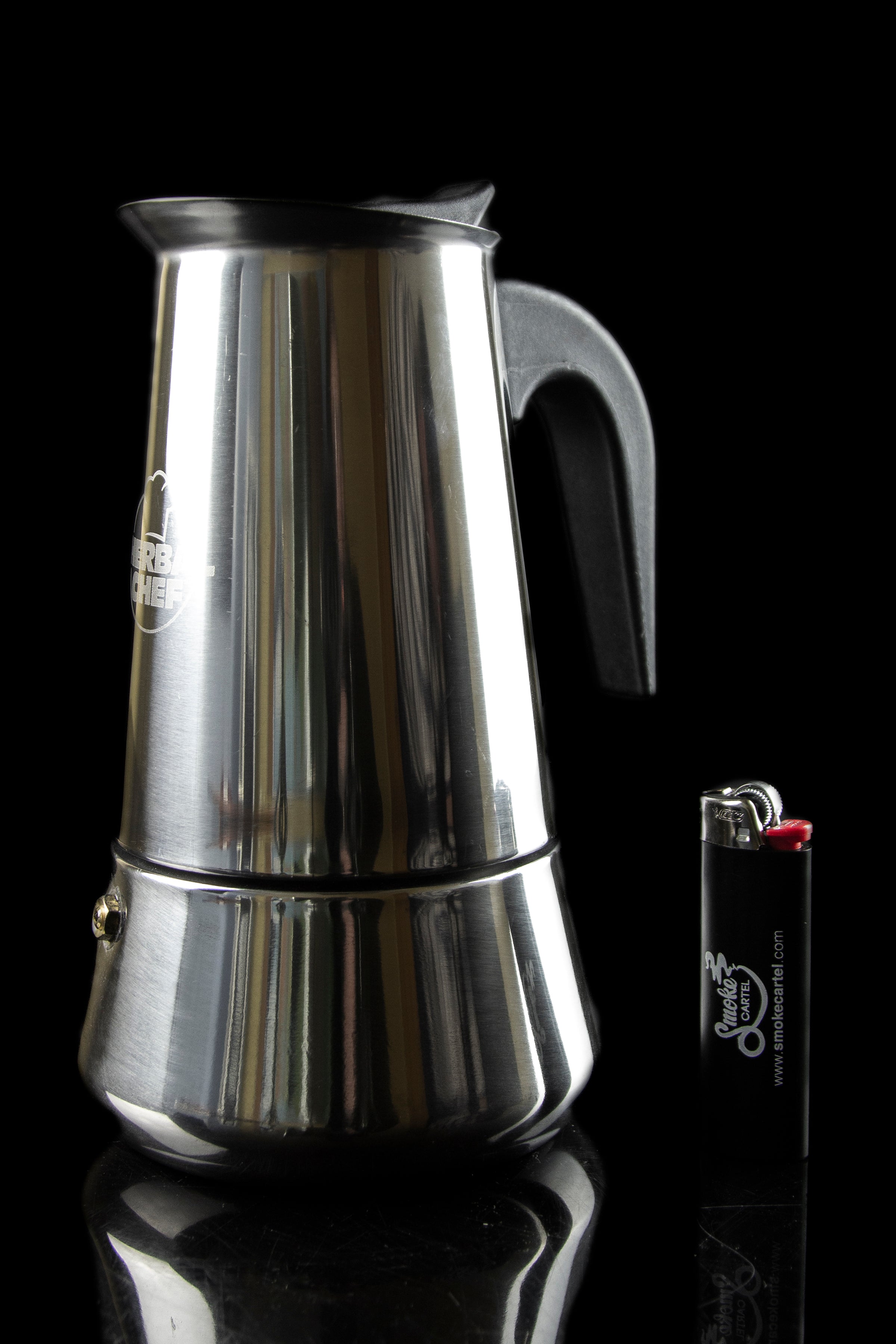 Silver stovetop espresso maker next to a lighter, reflecting on a dark surface.