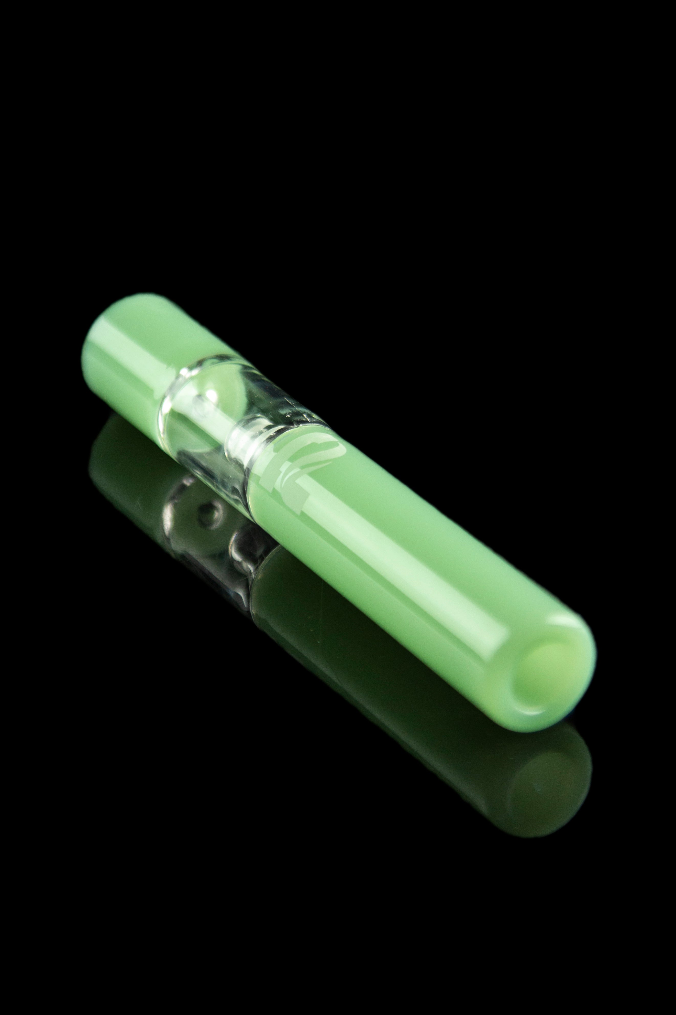 Green glass chillum with a visible chamber, reflecting on a black surface.