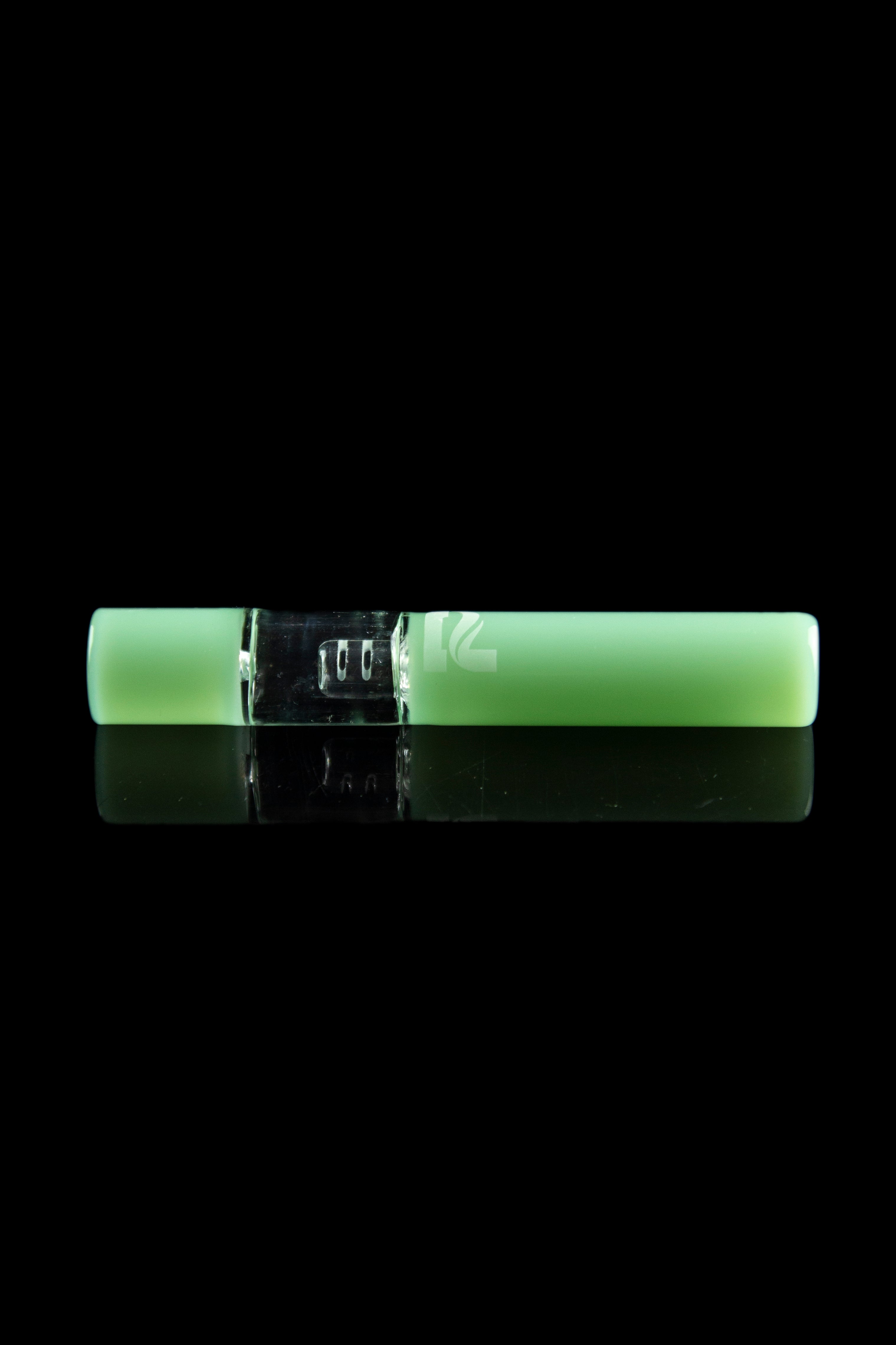 Glowing green cannabis oil vape pen with a metallic center section, displayed on a reflective black surface.