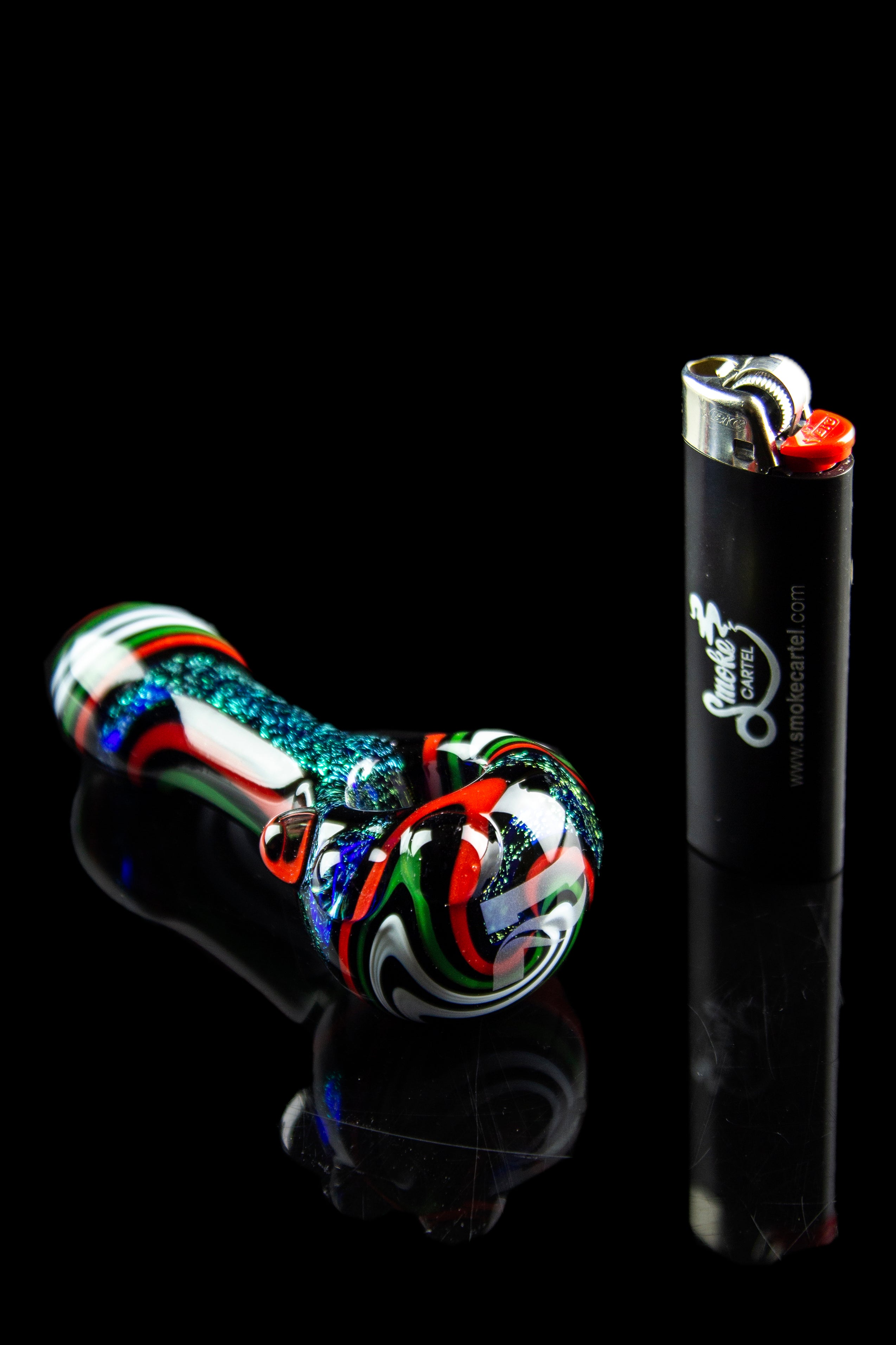 Colorful glass pipe and lighter on a black reflective surface.