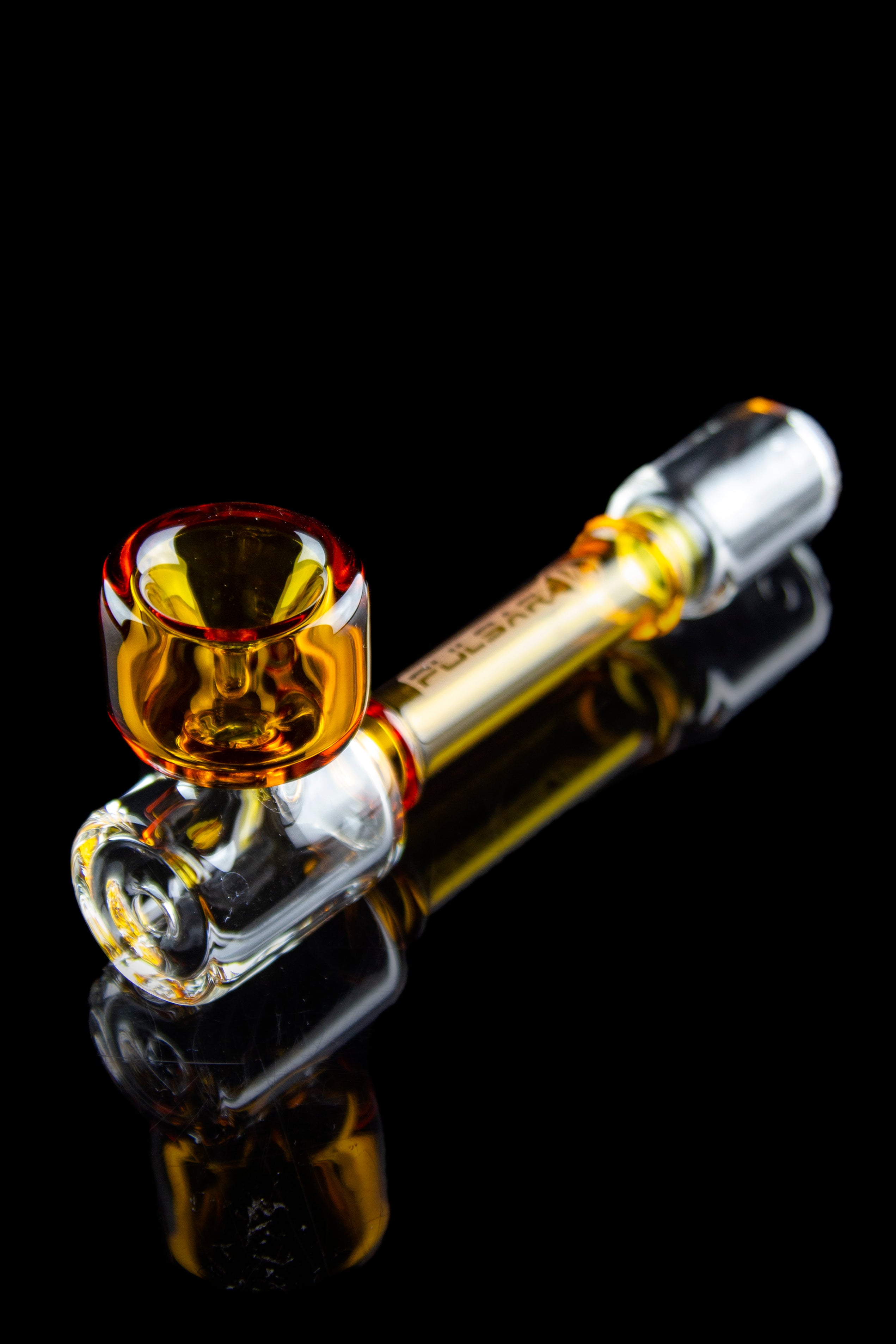A vibrant orange and clear glass pipe with a bulbous bowl, reflected on a dark surface.