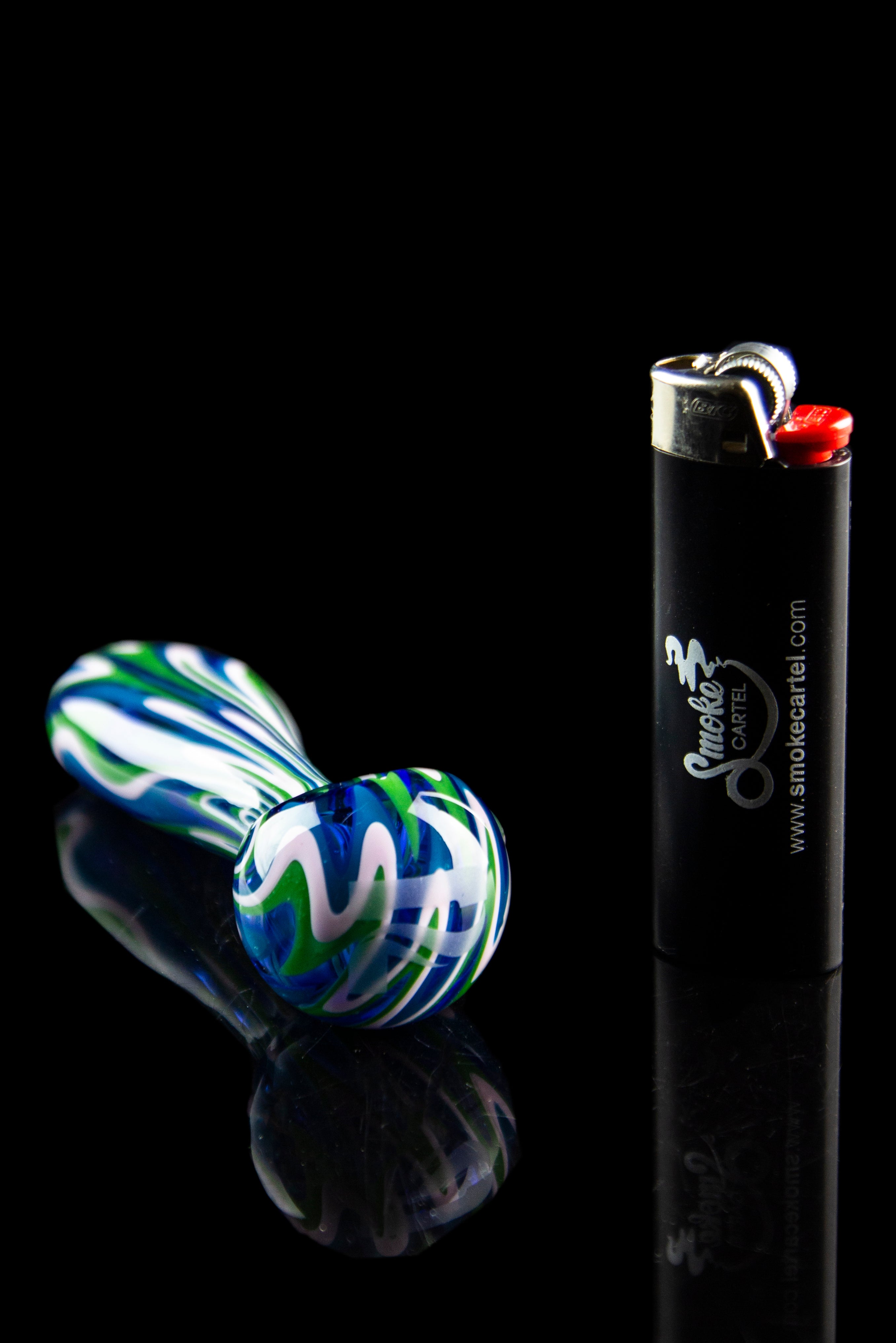A vibrant, colorful glass pipe and lighter against a black reflective surface.