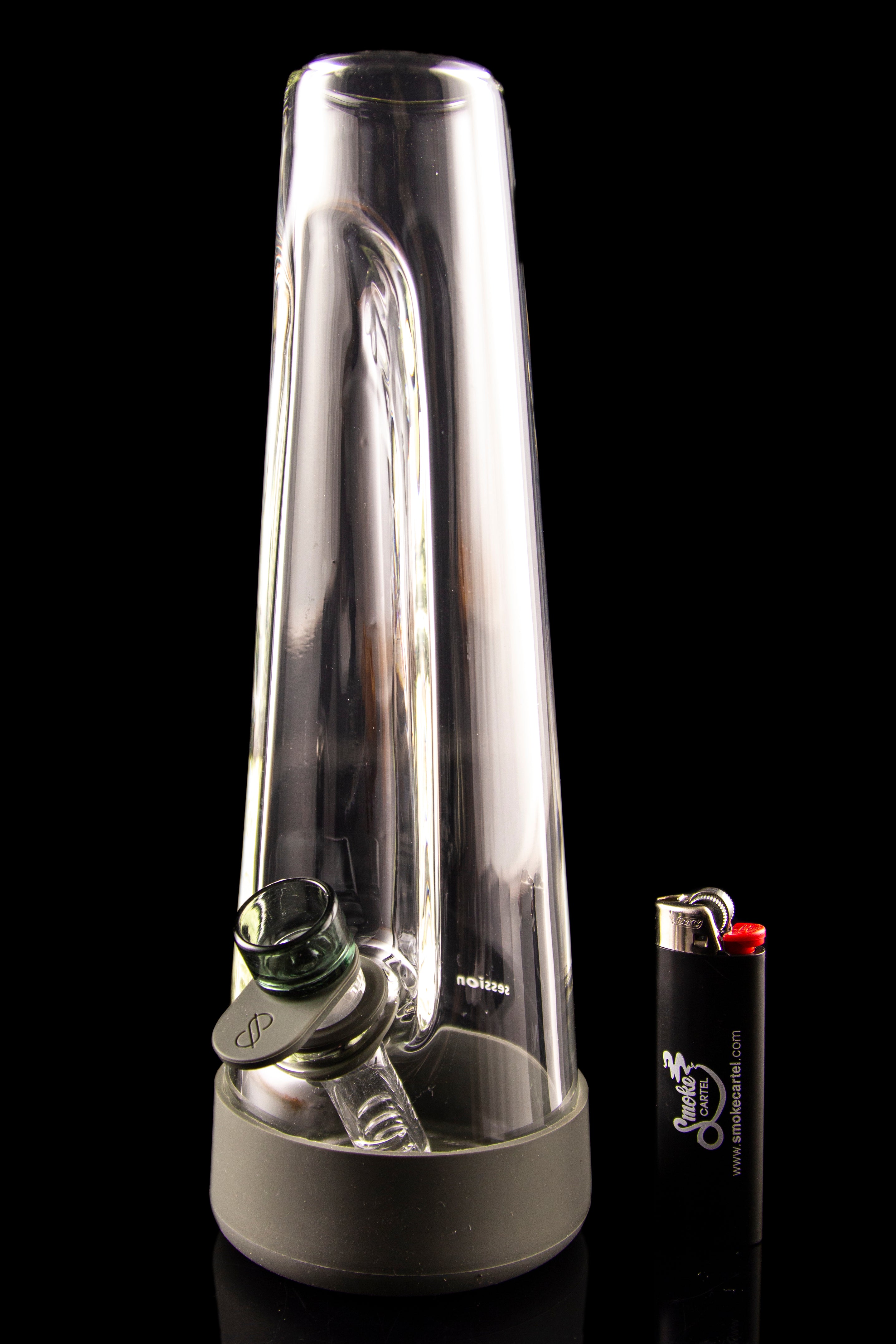 Clear glass bubbler with a green mouthpiece and lighter beside it, against a black background.