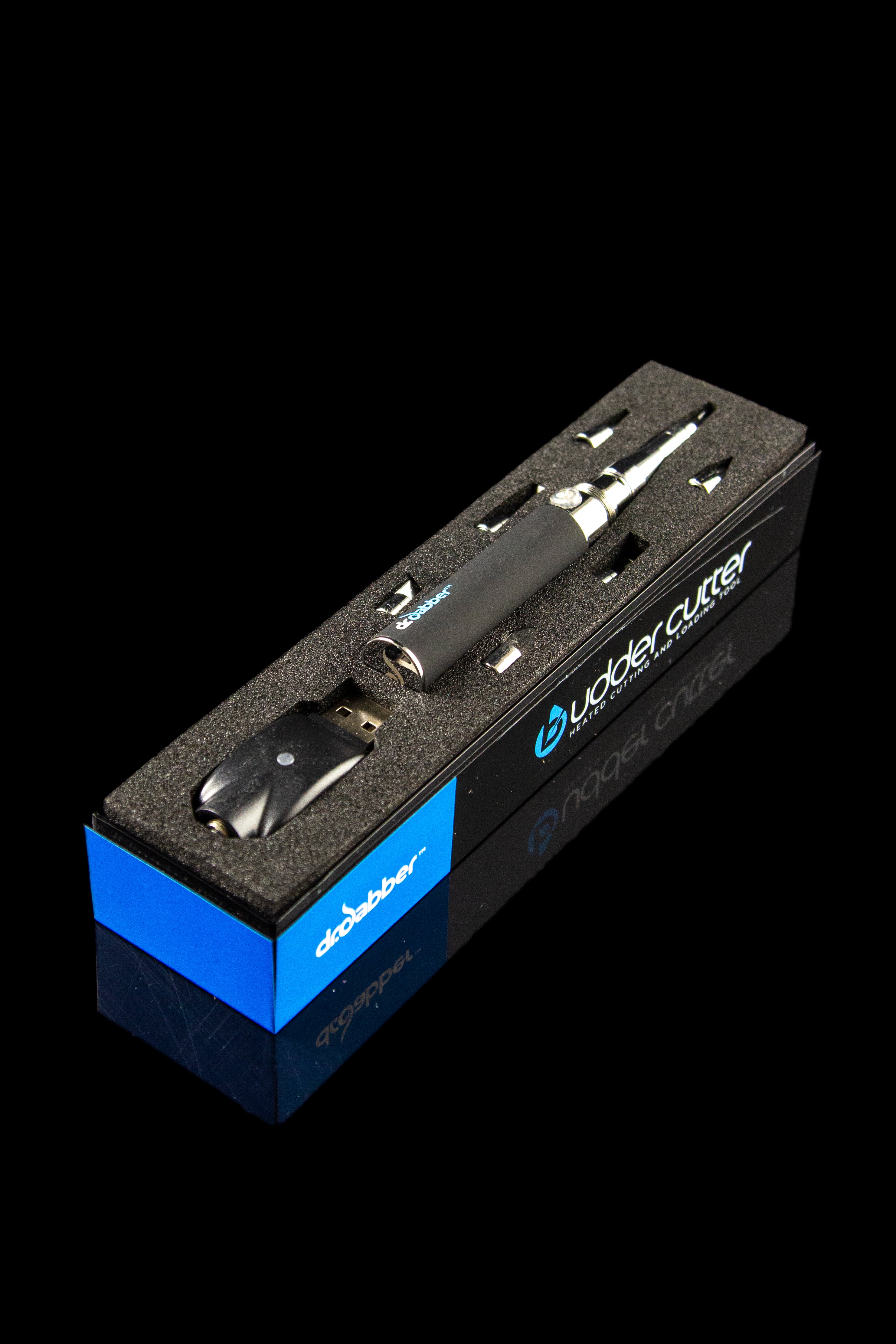 A close-up shot of the Dr. Dabber Budder Cutter tool on a dark background, showcasing its sleek metallic design and compact size.