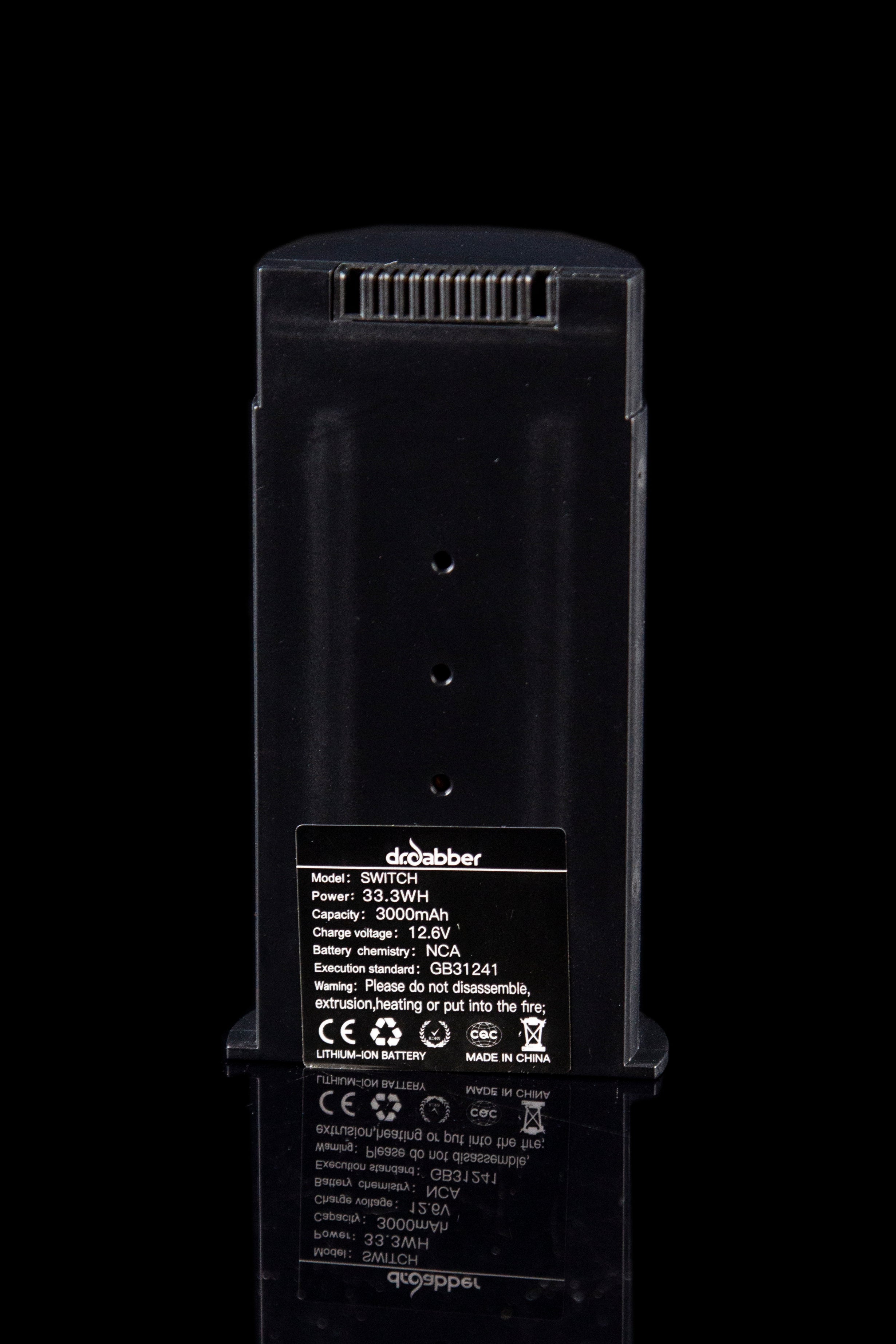 Close-up of a black “Droolubber Switch” portable power bank with technical specifications and warning labels, likely used for a cannabis vaporization device.