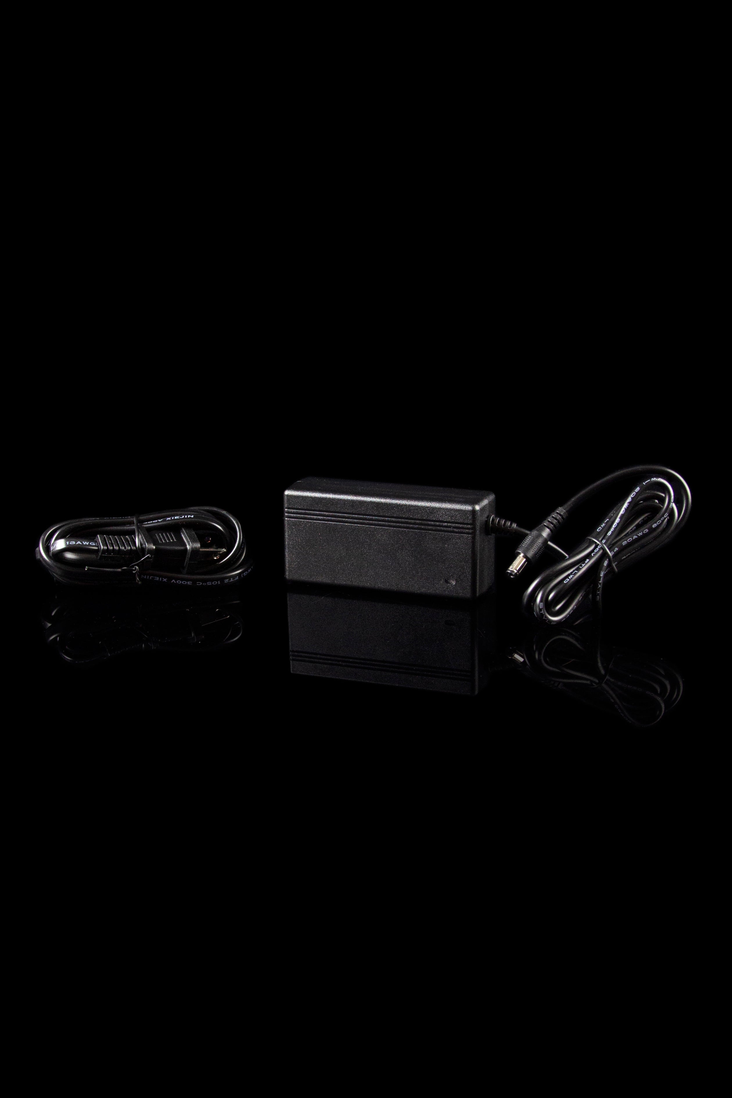 Black cannabis oil vaporizer pen charging kit with USB adapter and cord, studio shot.