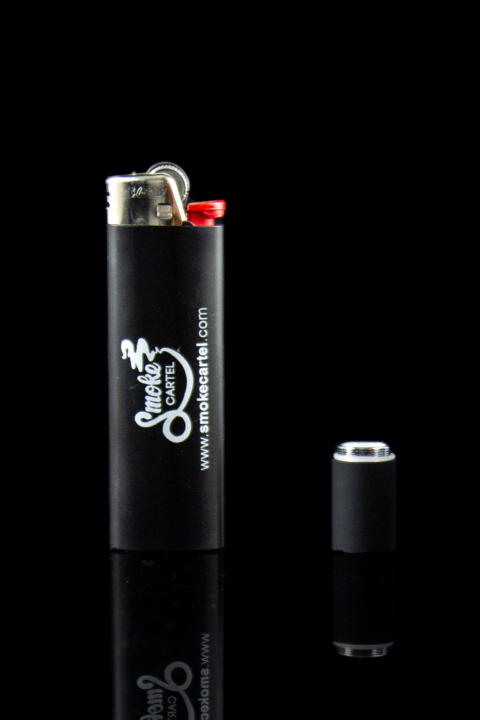 Black lighter with "Smoke Cartel" branding and disassembled components reflecting on a dark surface.