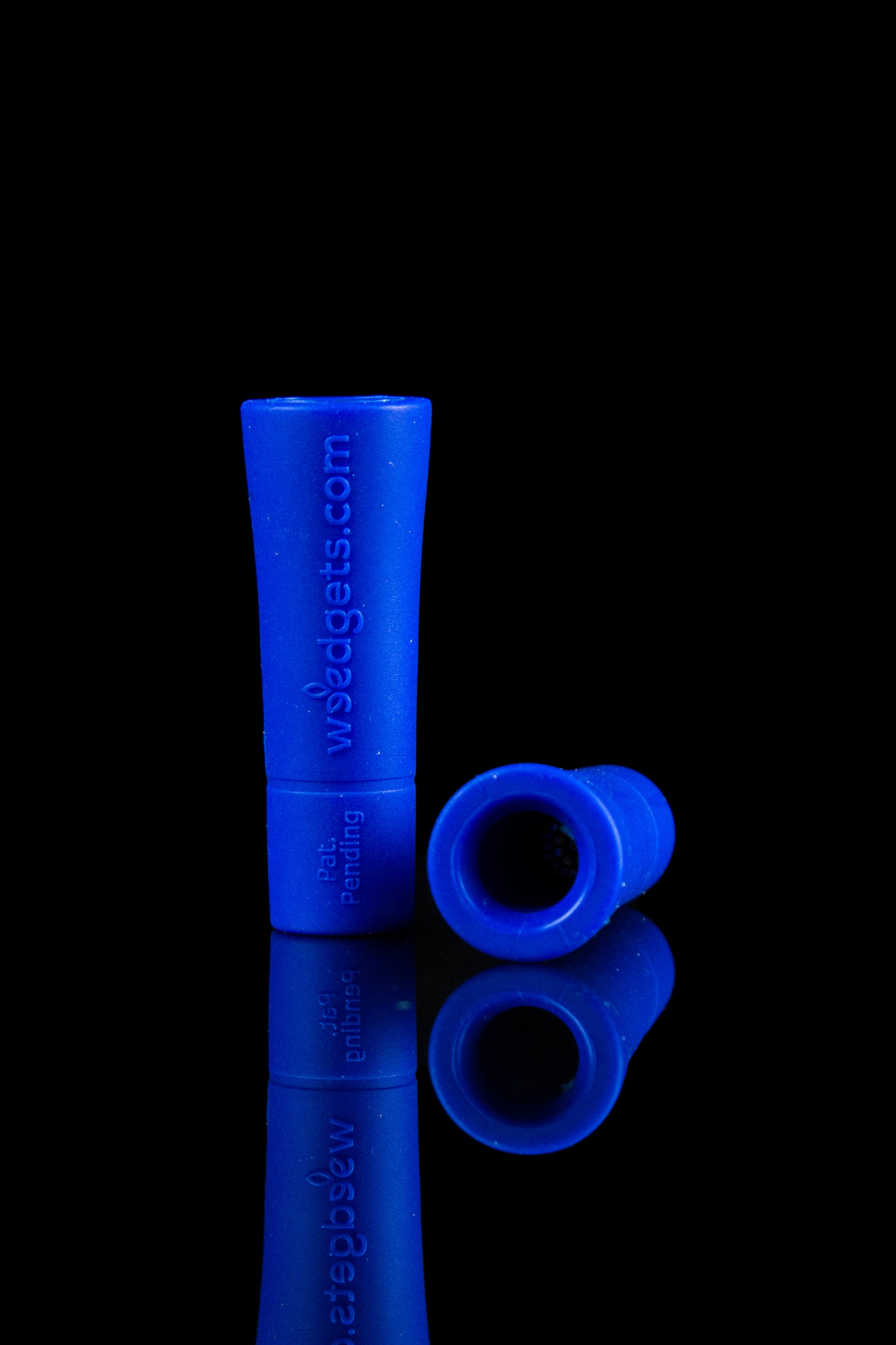 Blue glass cannabis pipe and mouthpiece reflecting on a black surface.