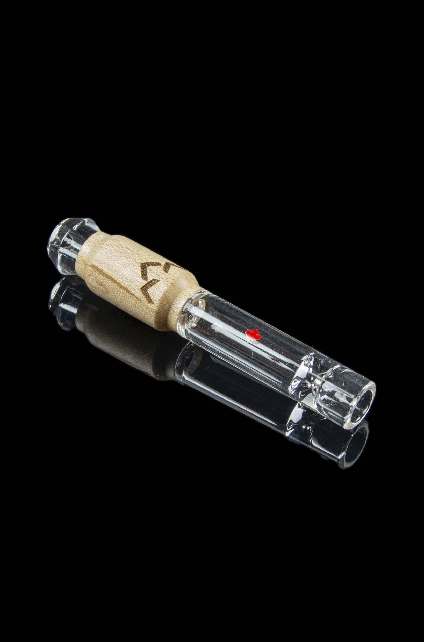 Clear glass smoking pipe with a wooden mouthpiece, reflecting on a black surface.