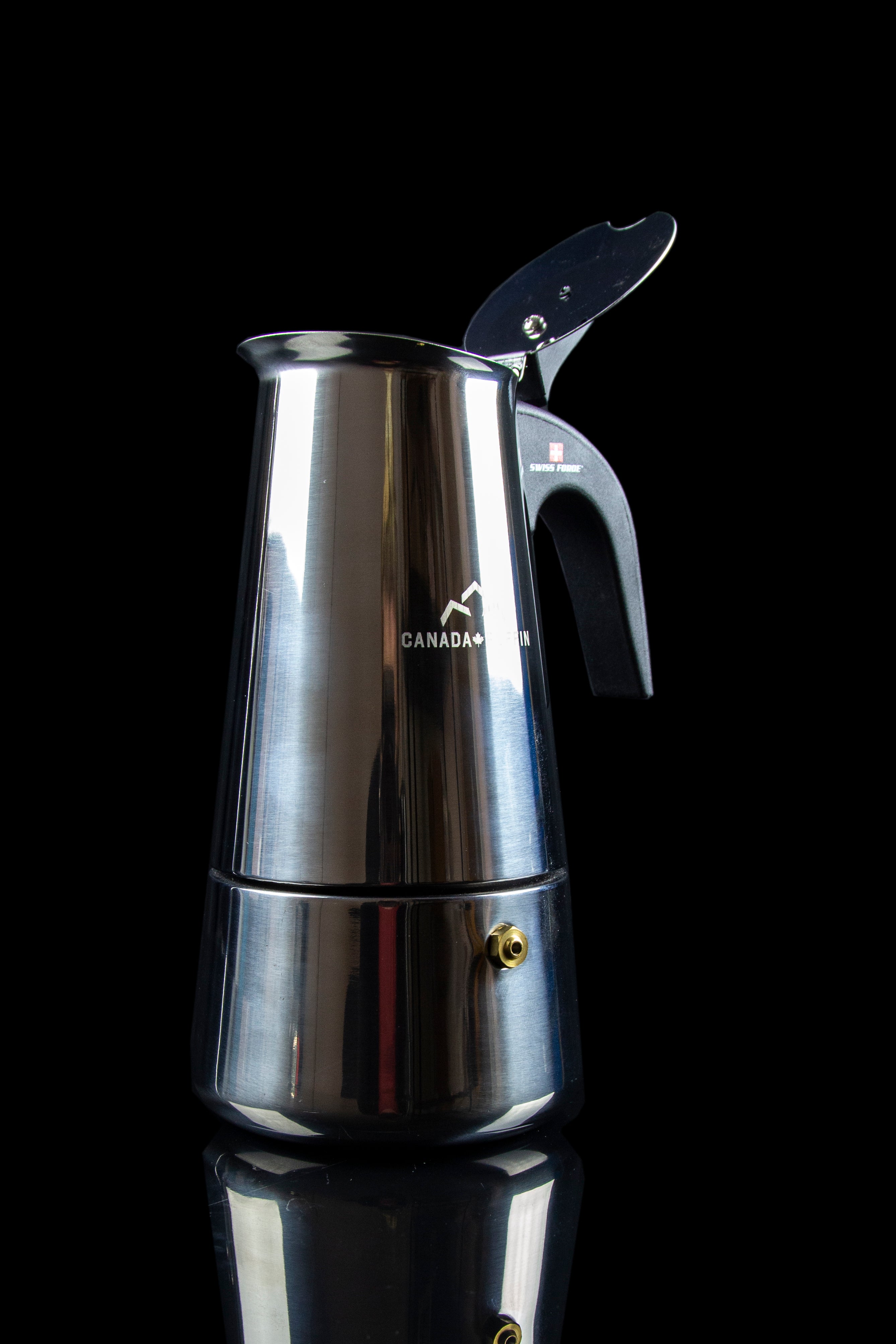 Silver stovetop espresso maker with a cannabis leaf logo and “Canada” inscribed on its side, reflecting on a dark surface.