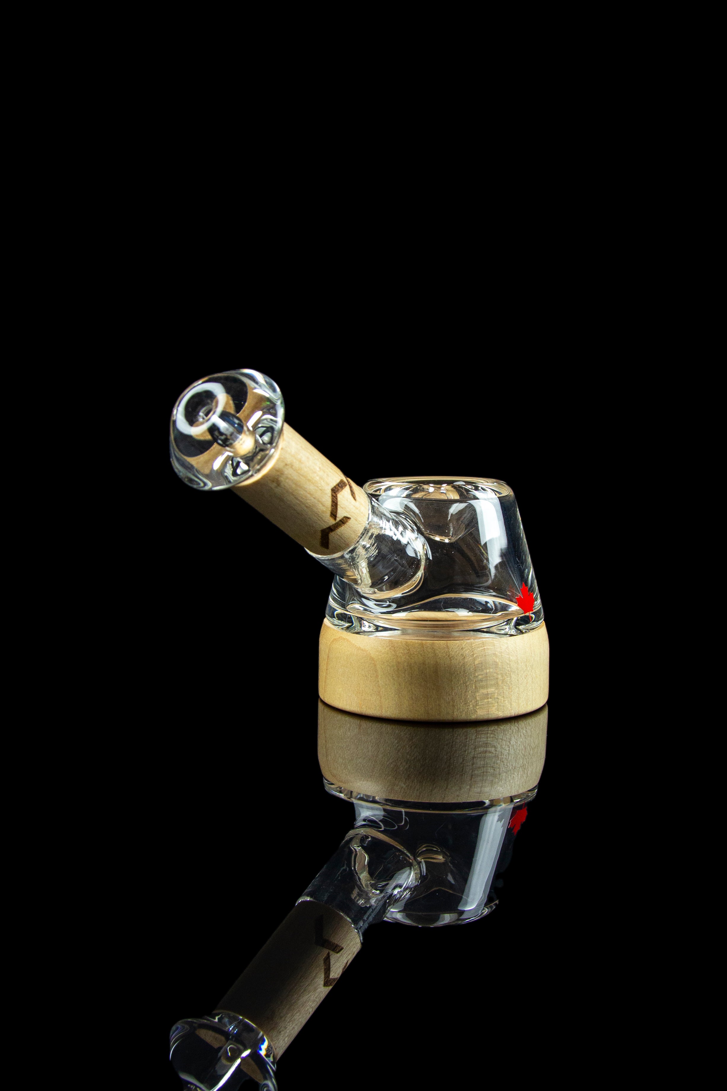 A glass cannabis rig with a wooden accent, isolated on a black reflective surface.