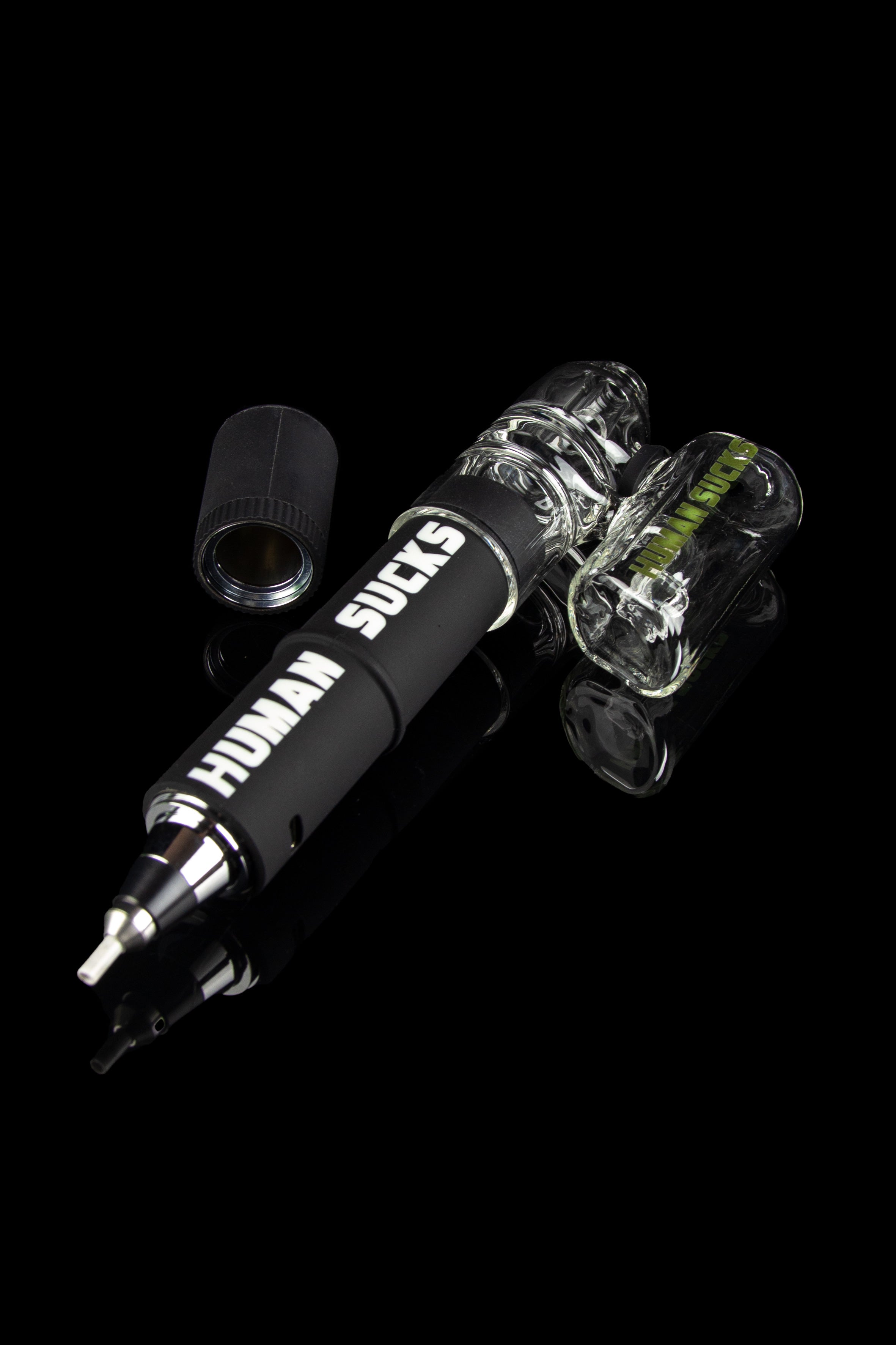 Black electronic dab rig with glass bubbler, displaying “HUMAN SUCKS” text, against a dark background.