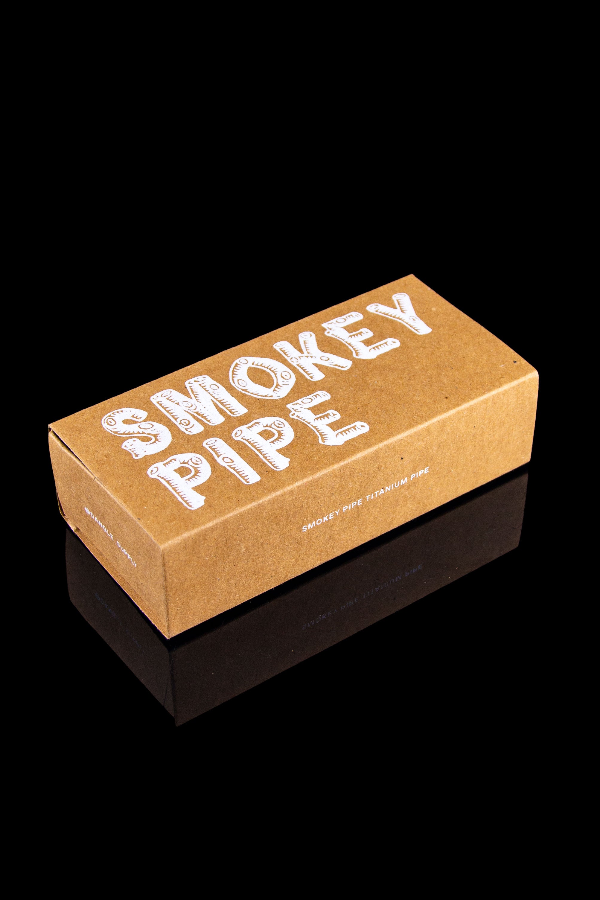 Cardboard box for “Smokey Pipe” titanium pipe, reflecting on a glossy black surface.