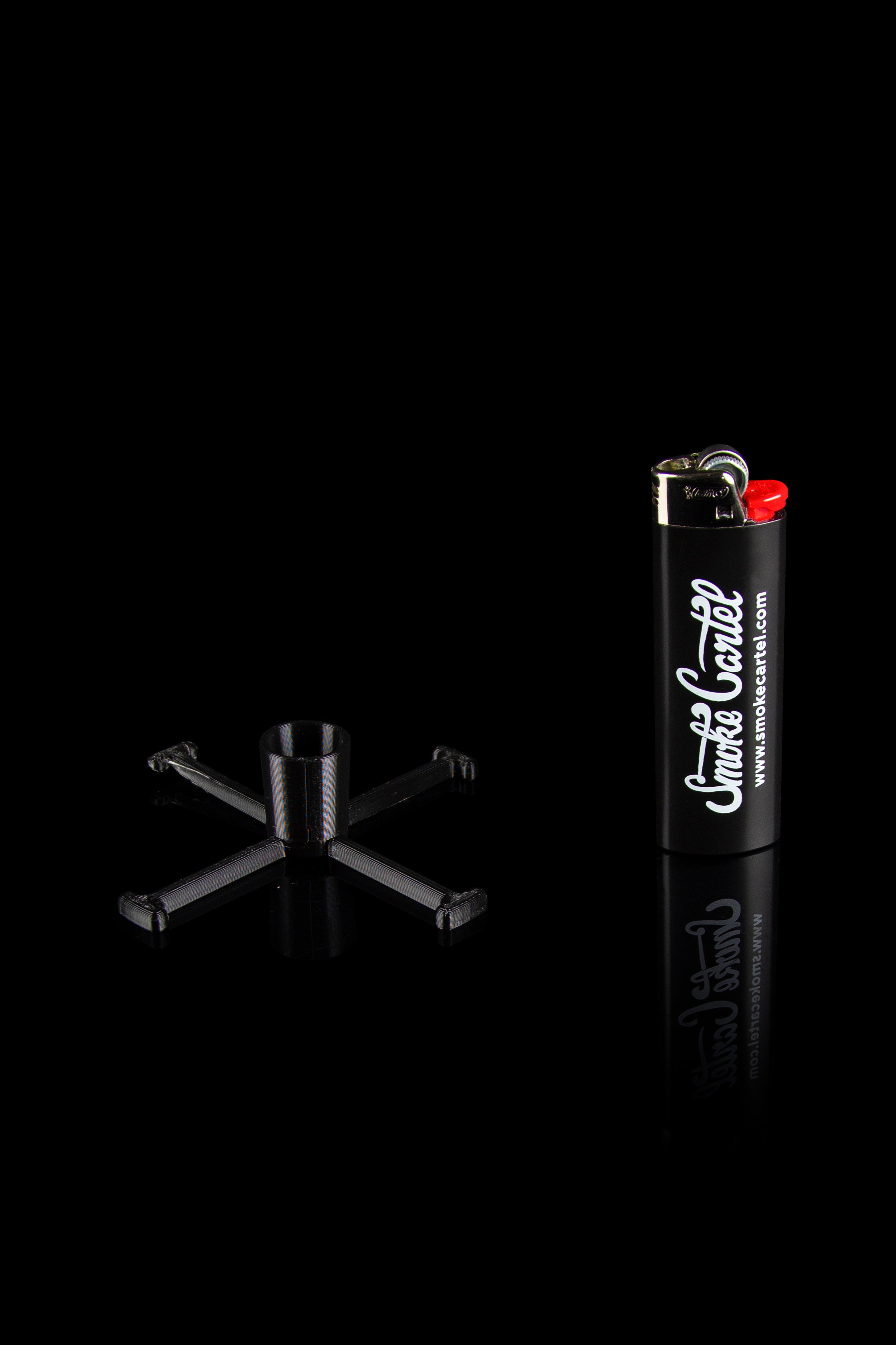 Black cannabis smoking accessories including a bubbler pipe and lighter with "Smoke Cartel" branding, isolated on a black reflective surface.