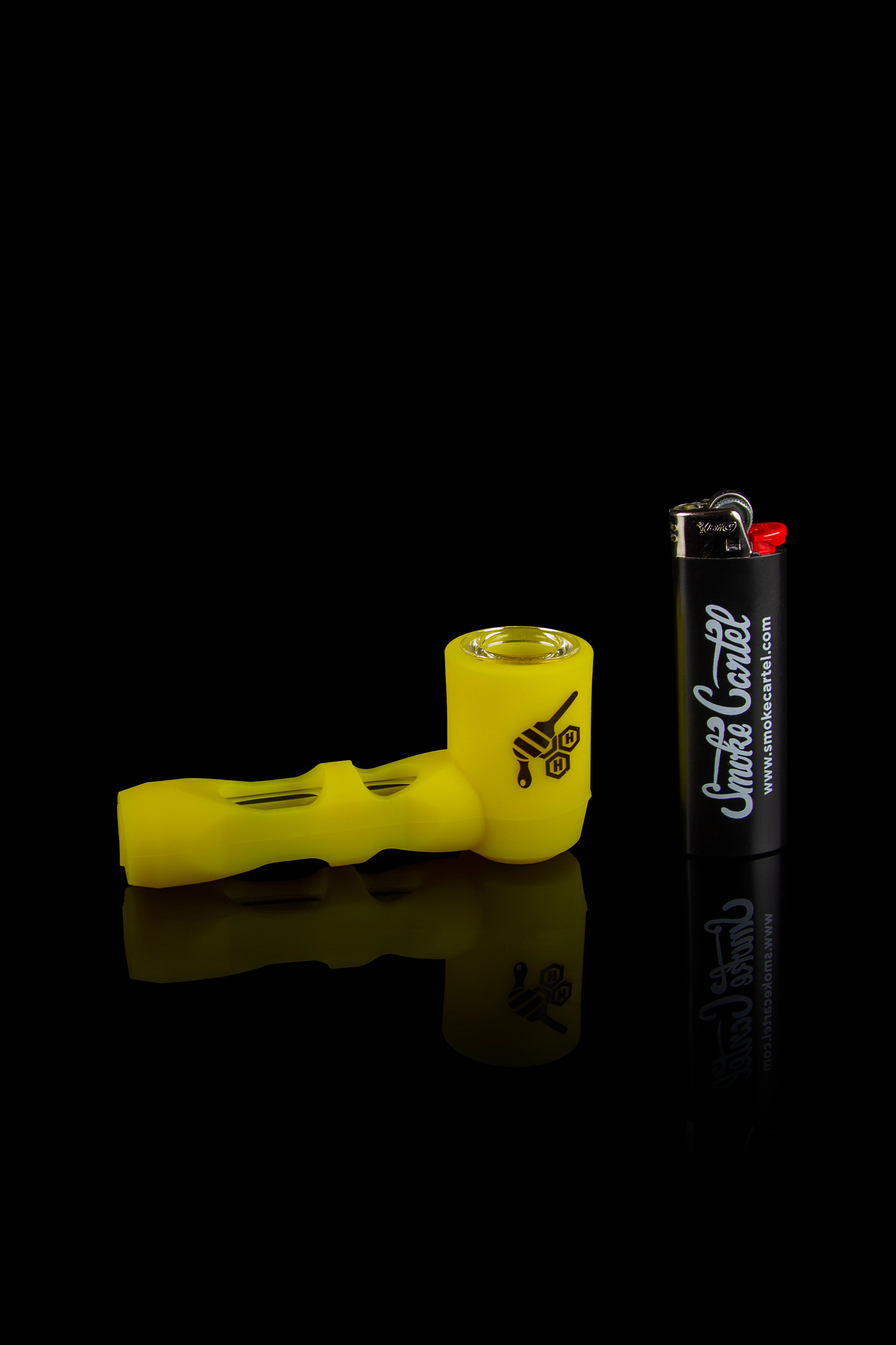 Yellow glass pipe and lighter on a reflective surface.