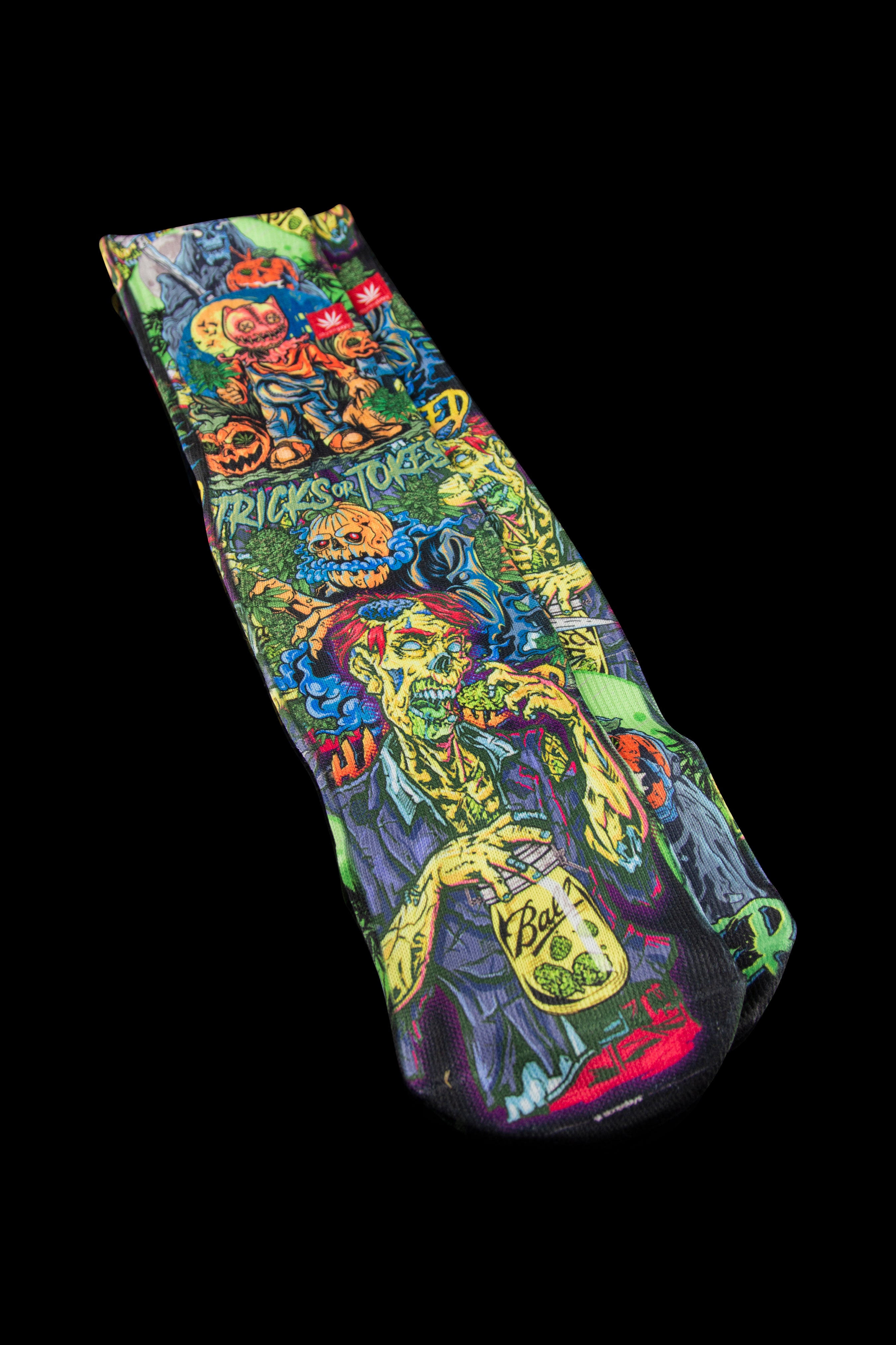 A vibrant, patterned cannabis sock designed to cover a smoking device, featuring spooky, colorful zombie-themed artwork and the text "TRICK OR TOKED".