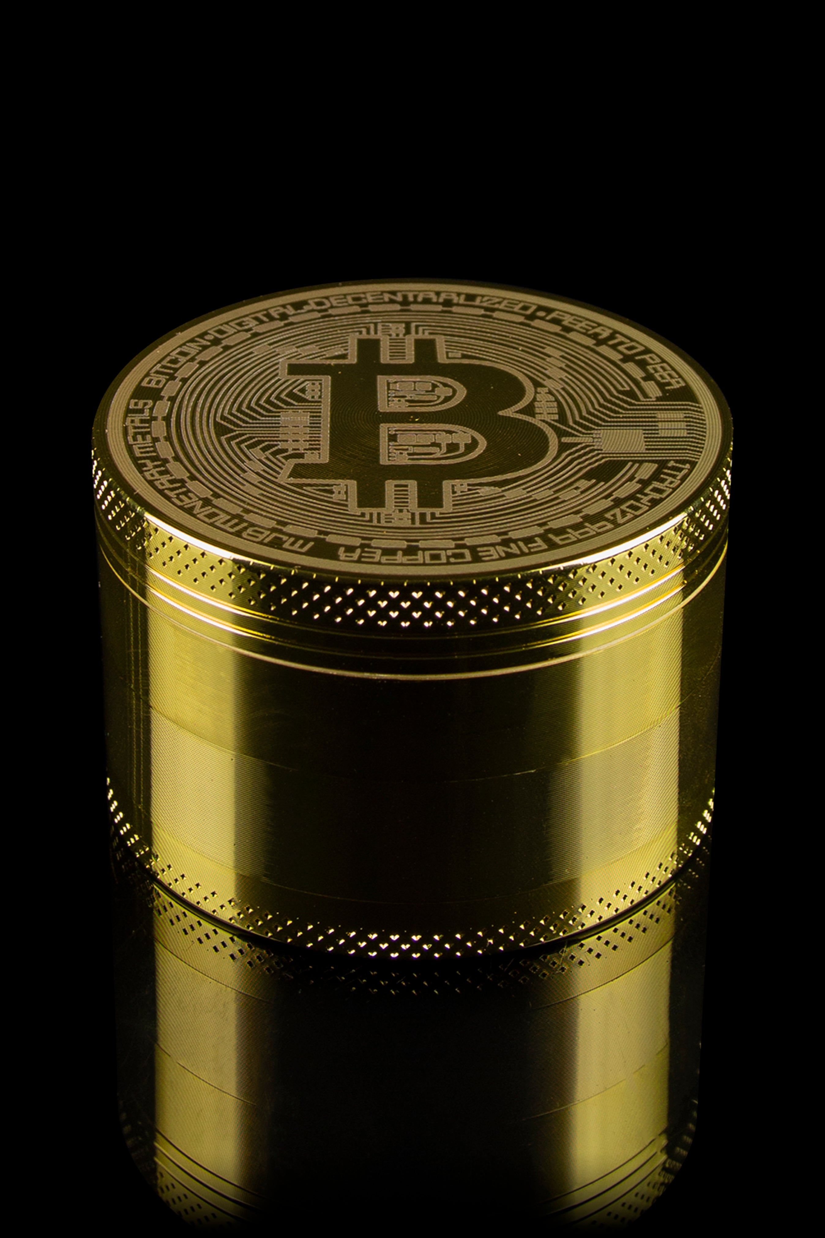 Gold cannabis grinder with a Bitcoin symbol etched on top.